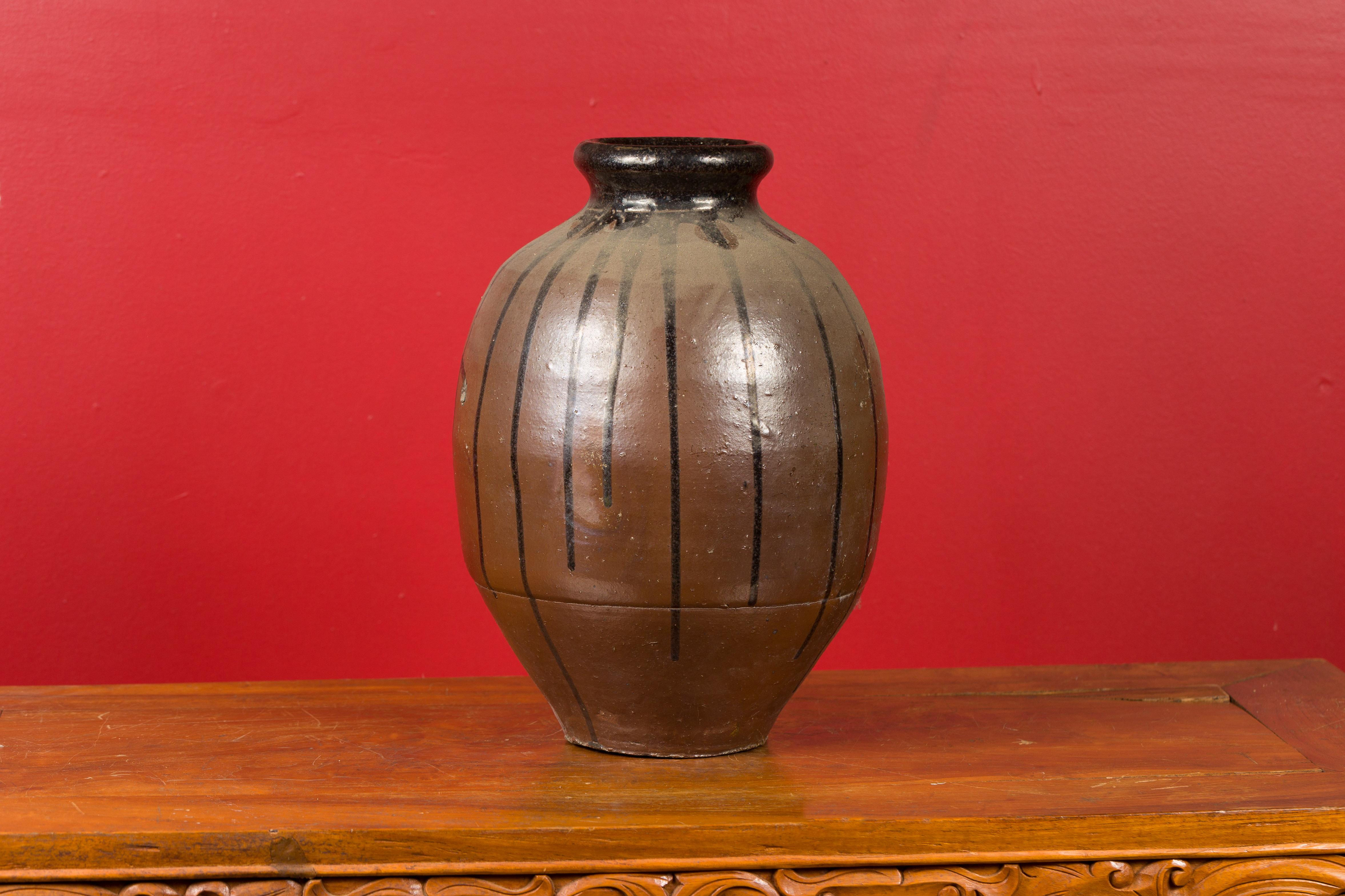 A Japanese Meiji period brown vase from the 19th century with black glazed accents. Created in Japan during the Meiji dynasty, this vase attracts our attention with its brown patina, delicately accented with black drippings. Topped with a rounded