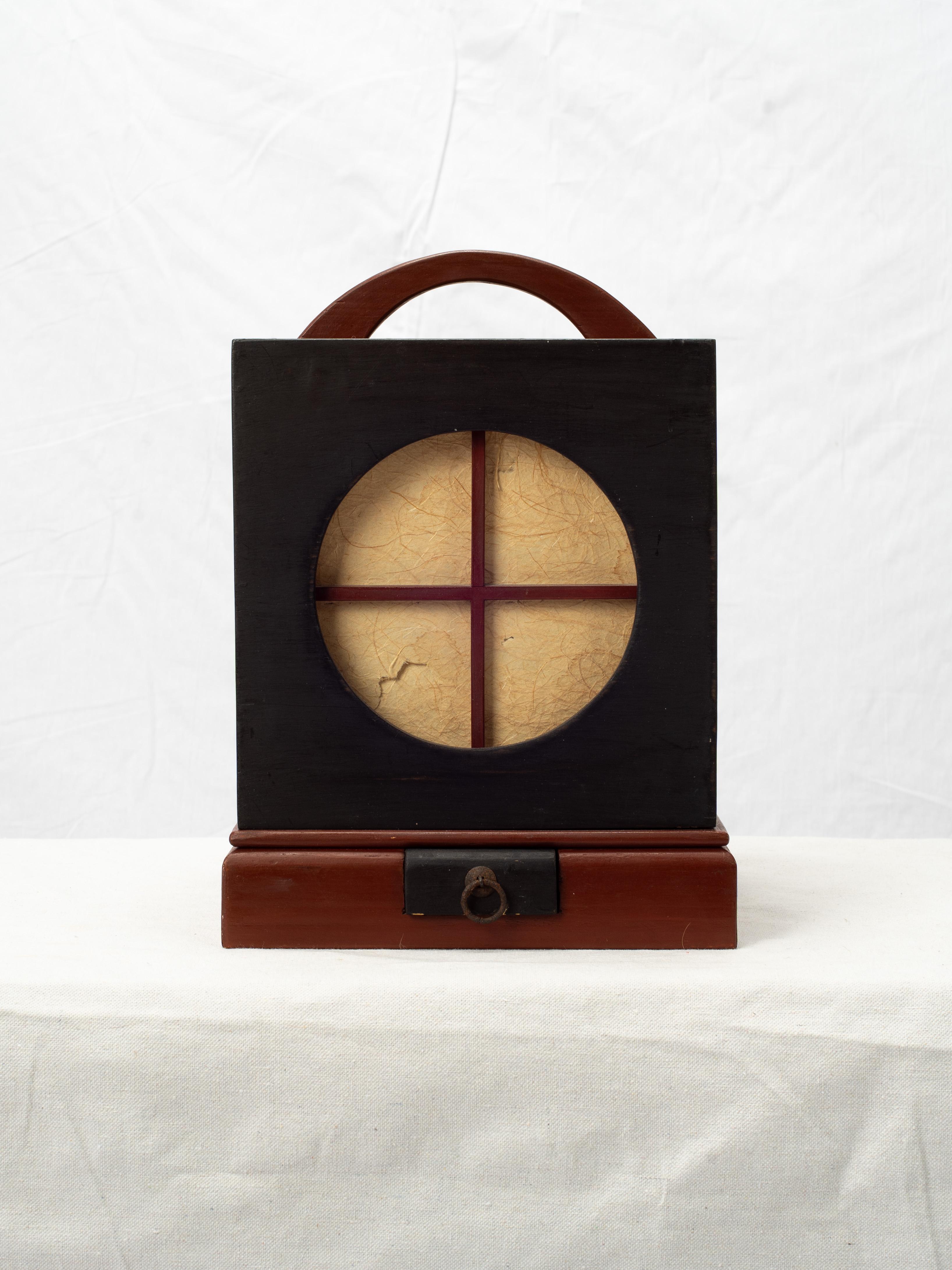 Traditional Japanese Ariake Andon are cube shaped lanterns, originally used as a kind of nightlight lamp.

With washi paper and a black and red lacquer wood frame and handle, the outer cover features circular and organic silhouette cutouts,