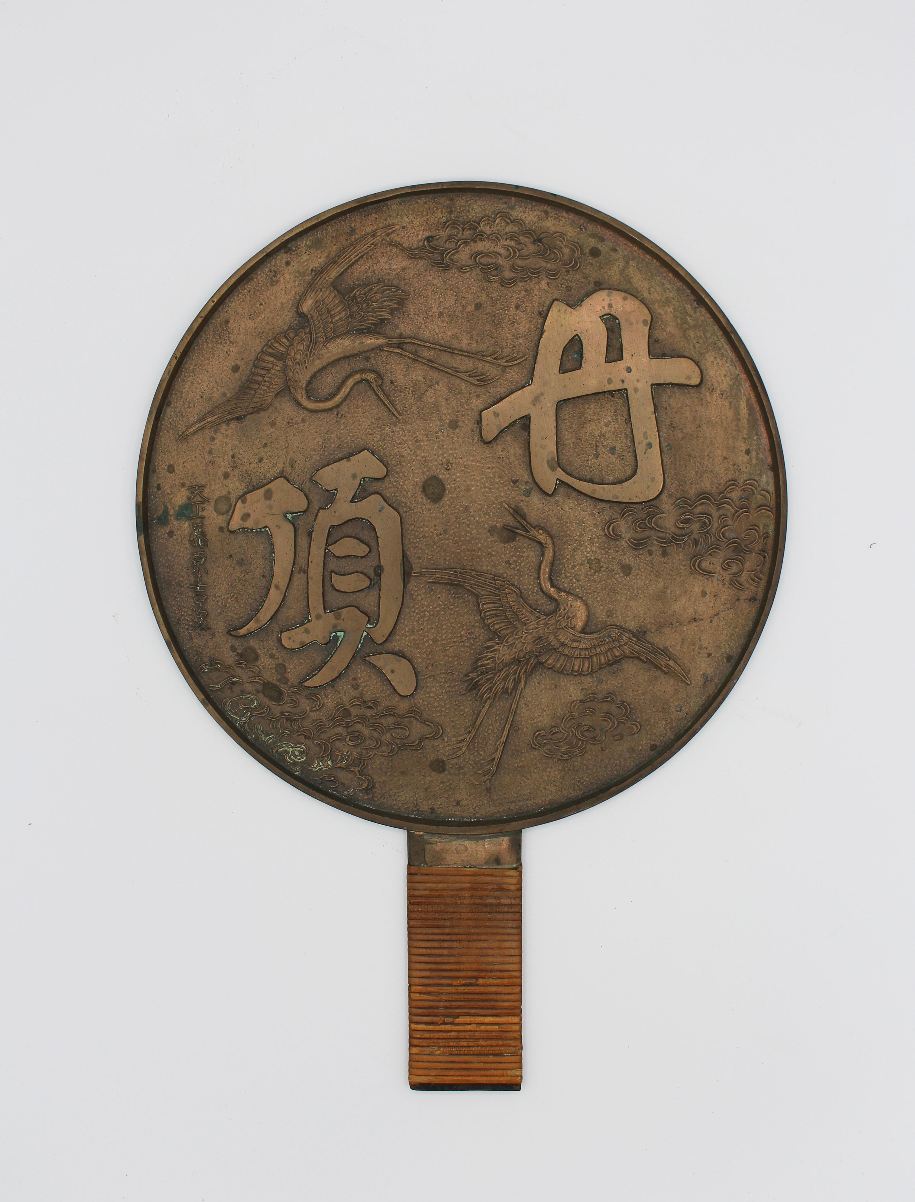 A Japanese bronze mirror of courting cranes with good rafia handle cover, Meiji period, 1868-1912. A very nice example, often bridal gifts. 9 1/2