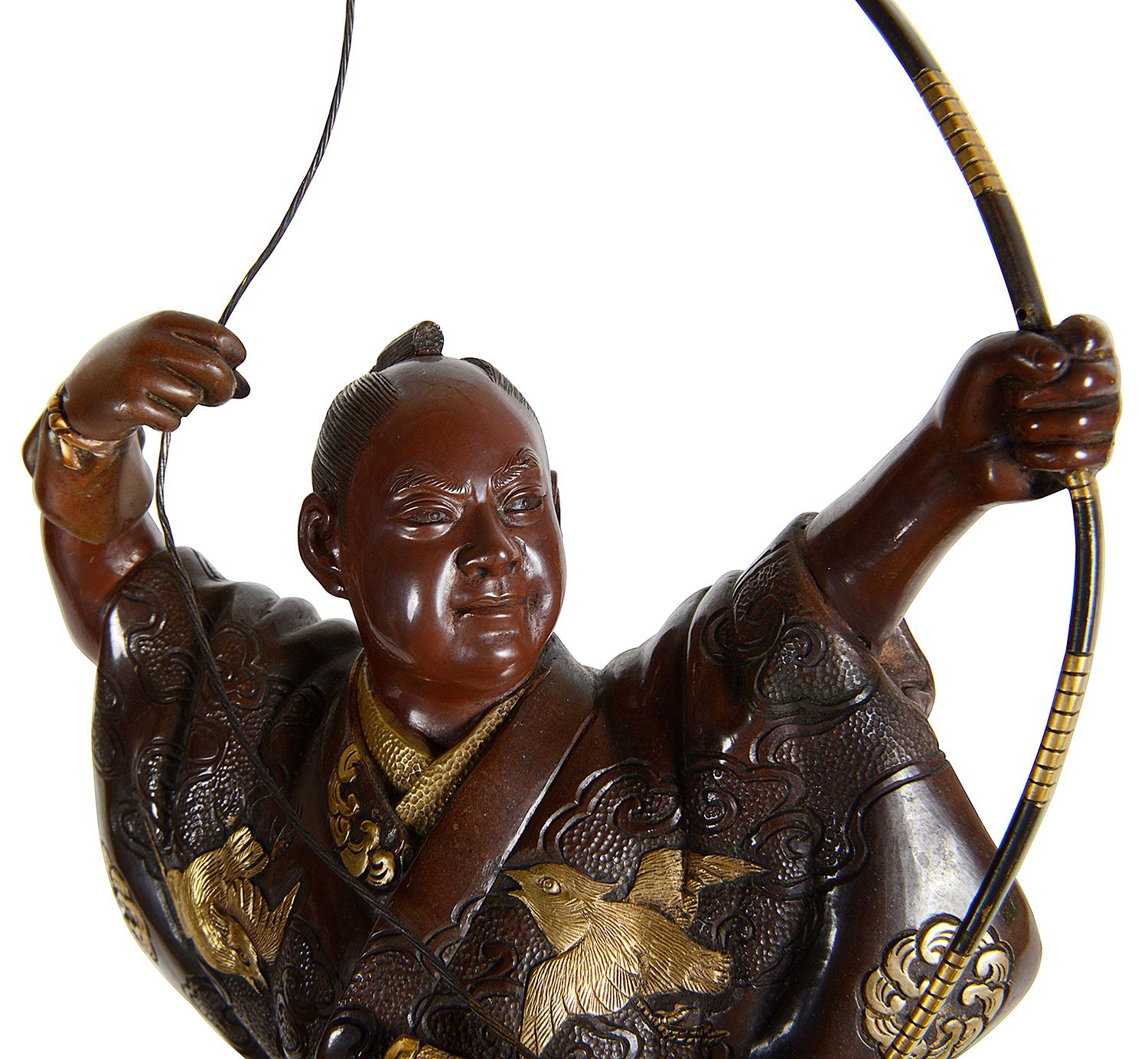 A fine quality Meiji period (1868-1912) Japanese patinated bronze statue of an archer, having gilded highlights, raised o a carved wood and gilded stand.
In the style of Miyao.