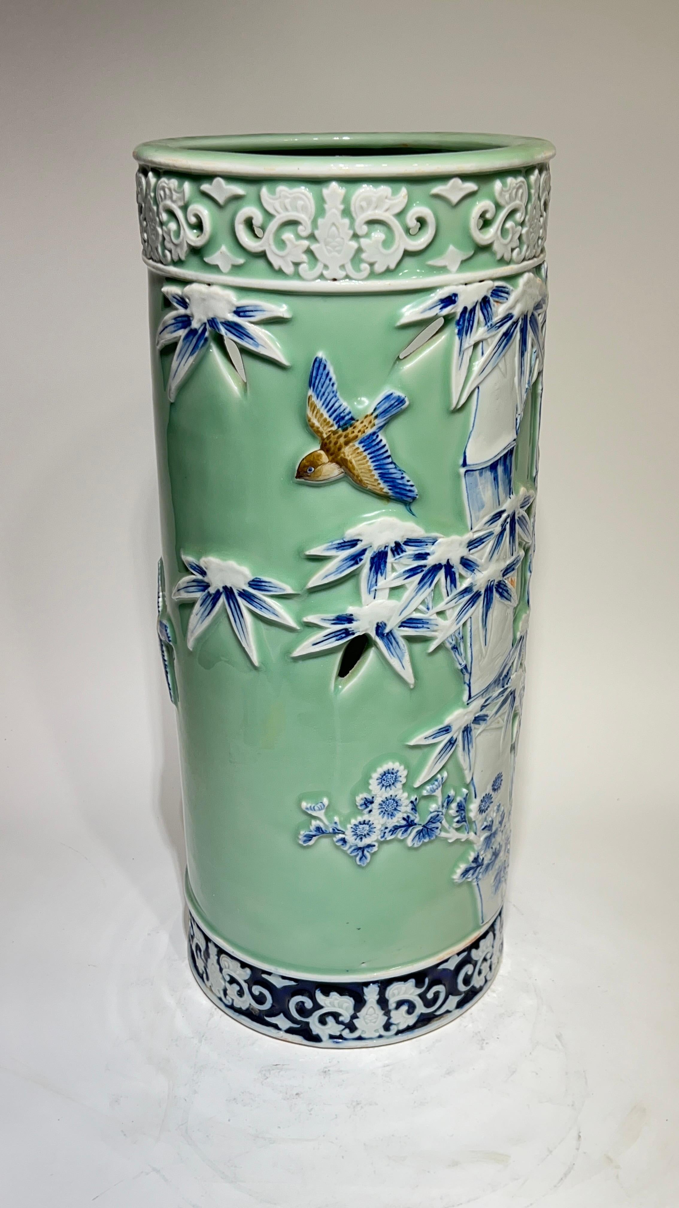 Muy buena calidad y Encantador  Paragüero de porcelana con diseños en relieve de pájaros en vuelo entre bambúes sobre fondo esmaltado celadón con bandas blancas en relieve de volutas en la parte inferior y superior.  Muy buen estado.  Aparentemente
