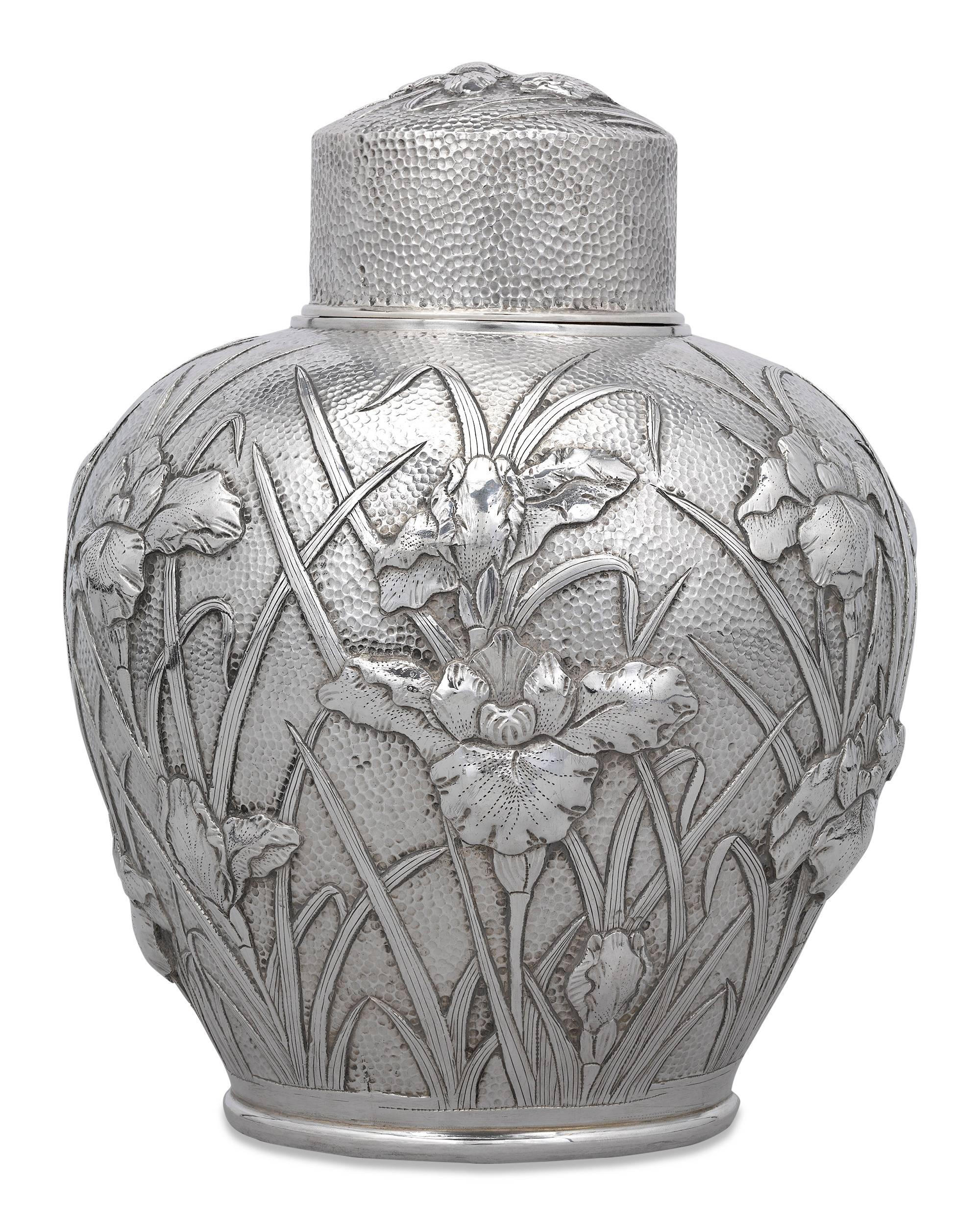 These exceptional Japanese silver tea canisters were crafted during Japan's highly creative Meiji period. The impeccable pair feature an intricate design of irises in high relief wrapped continuously around the canisters' hammered exteriors.