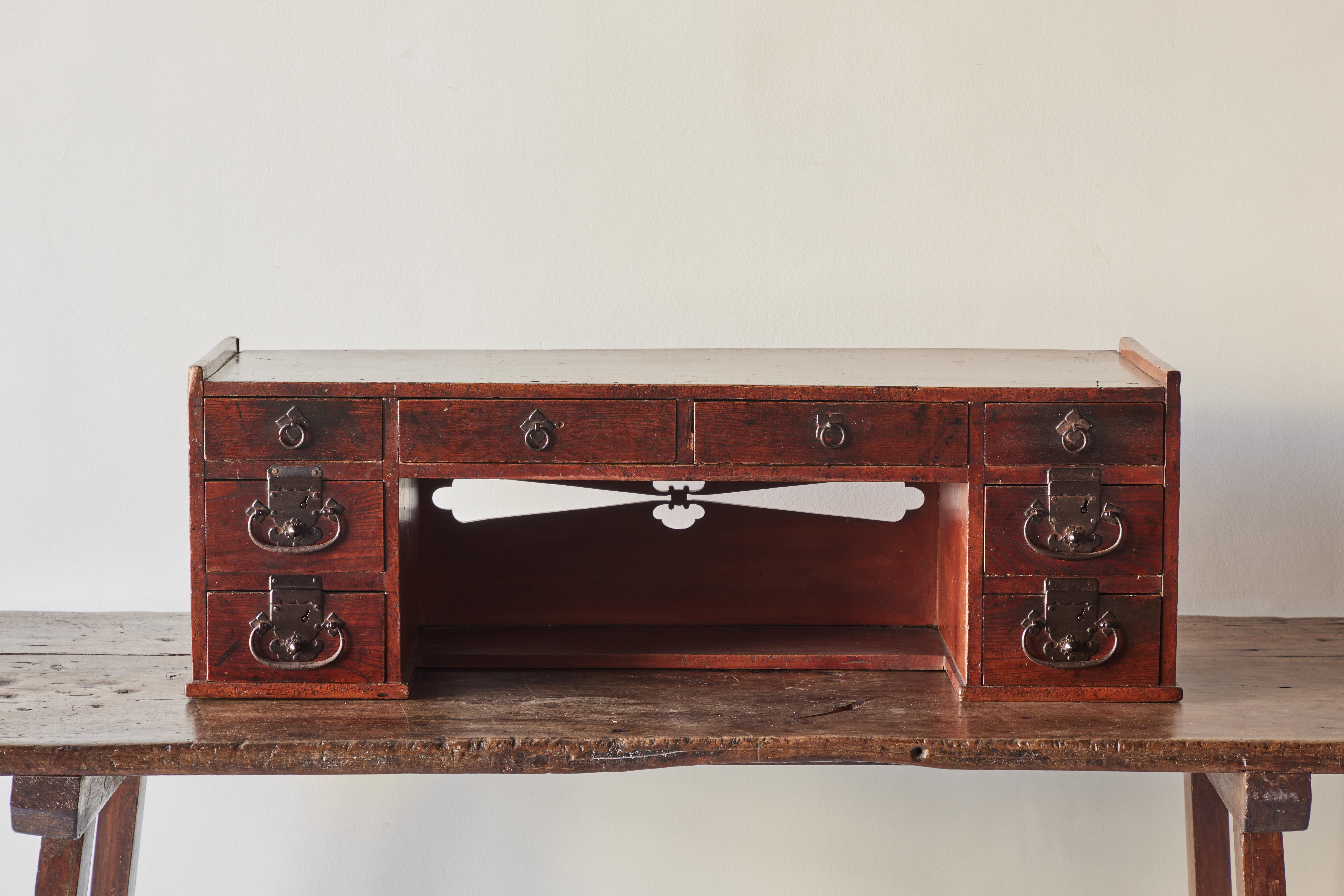 Low Japanese merchant’s desk from the Meiji Period (1868-1912). Made of solid wood and iron hardware, this low desk features eight small drawers for ample storage.