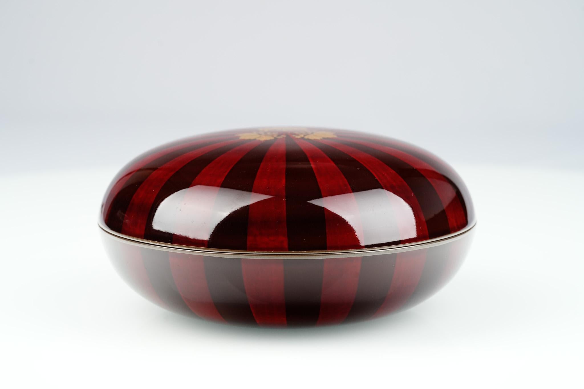 Diese Kashiki-Bonbonschale aus der Meiji-Zeit wirkt anmutig und würdevoll. Die runde Form ist mit zwei tiefroten Lacken lackiert, die in einem leuchtenden Muster angeordnet sind und mit eleganten goldenen Maki-Paulownia-Blättern akzentuiert werden.