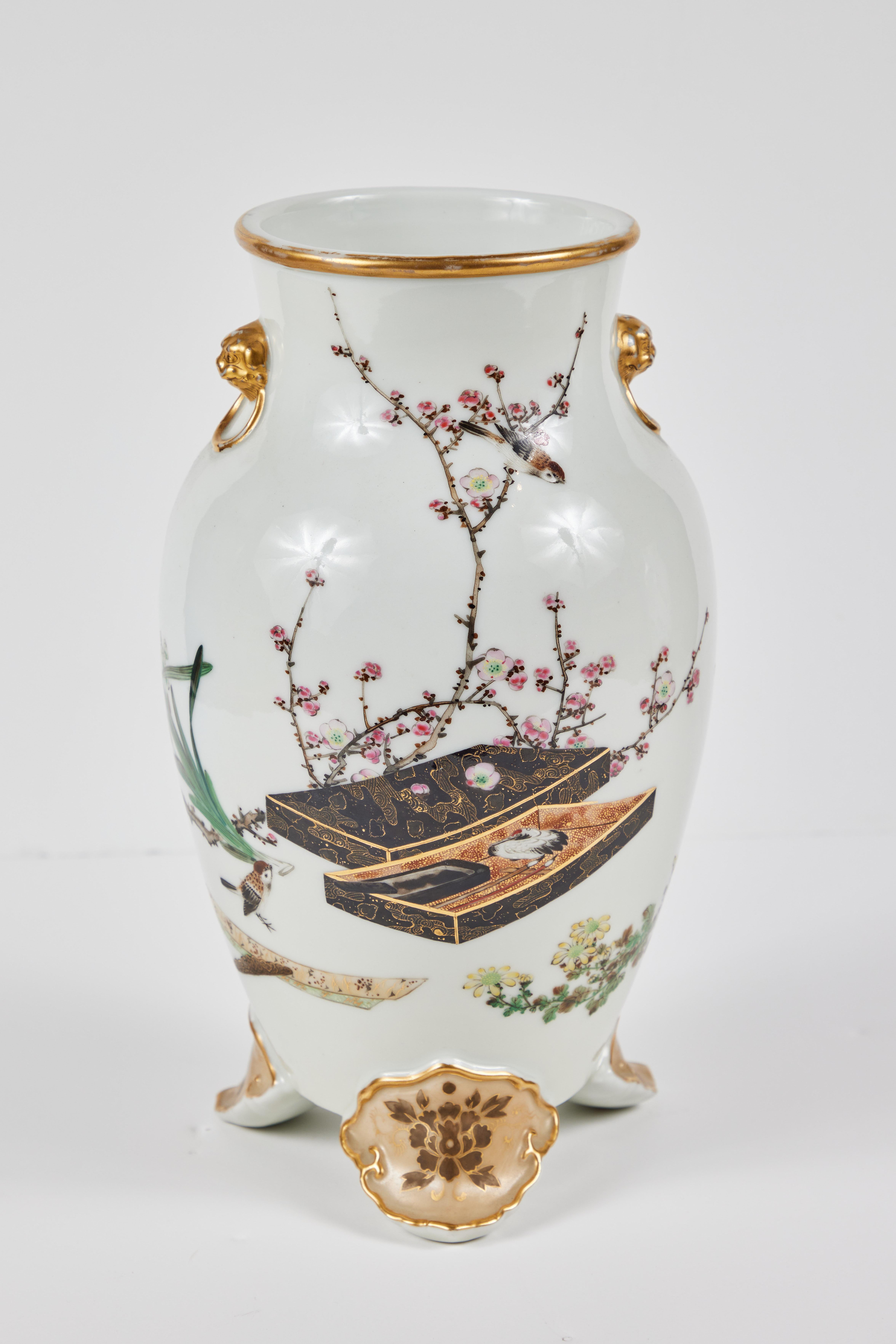 An elegant pair of hand-painted, parcel gilt, turn-of-the-century, Japanese vases on petal form feet. Each featuring images of calligraphy sets amidst flowering branches and birds.  Signed on the bottom.