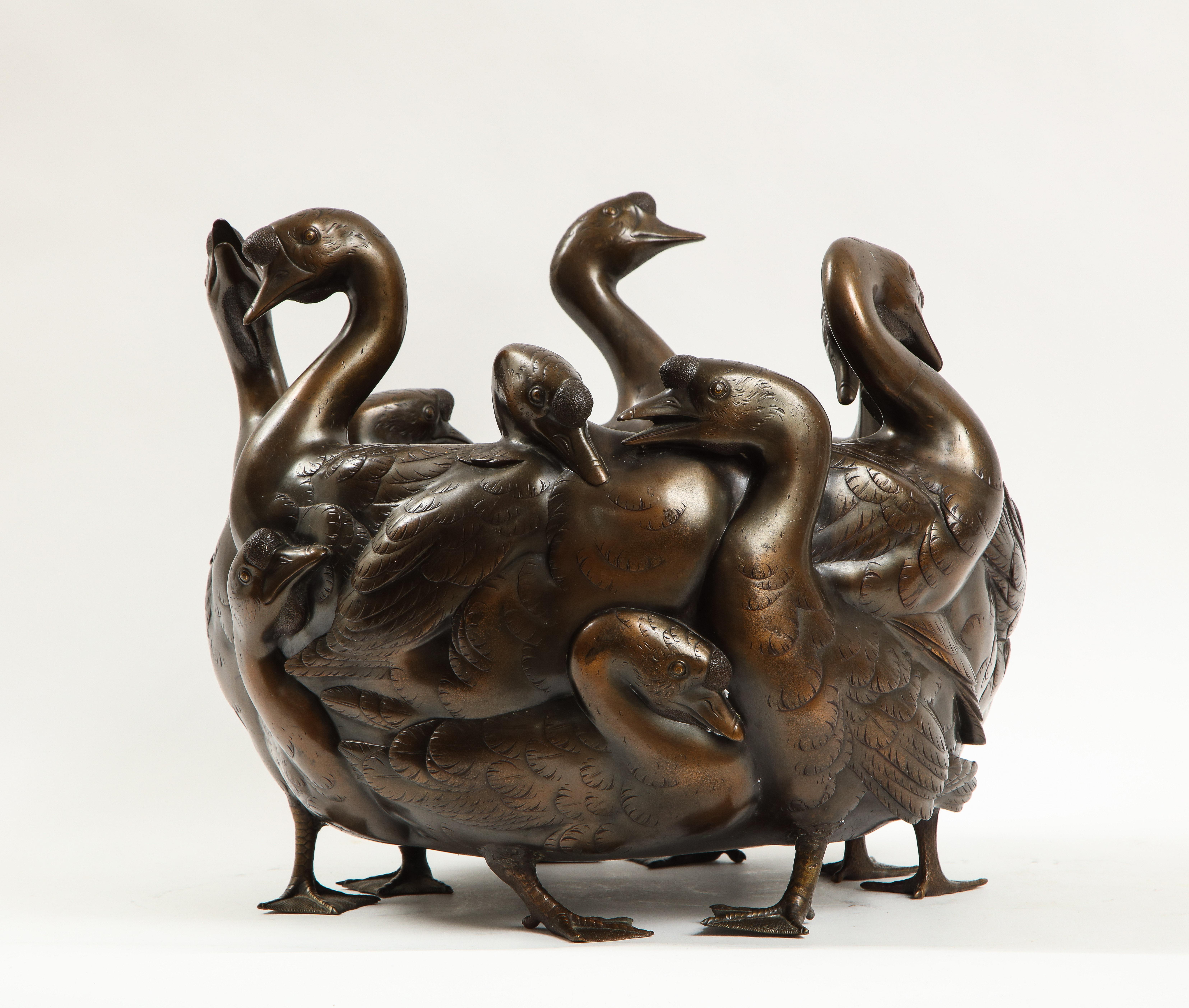 A very rare 19th/20th century Japanese bronze centerpiece of a flock of geese with heads cast in three dimensions, stamped and signed Gen Ryusai Seya. Each having gold inlaid eyes with all sections of their bodies hand-chassed with the finest