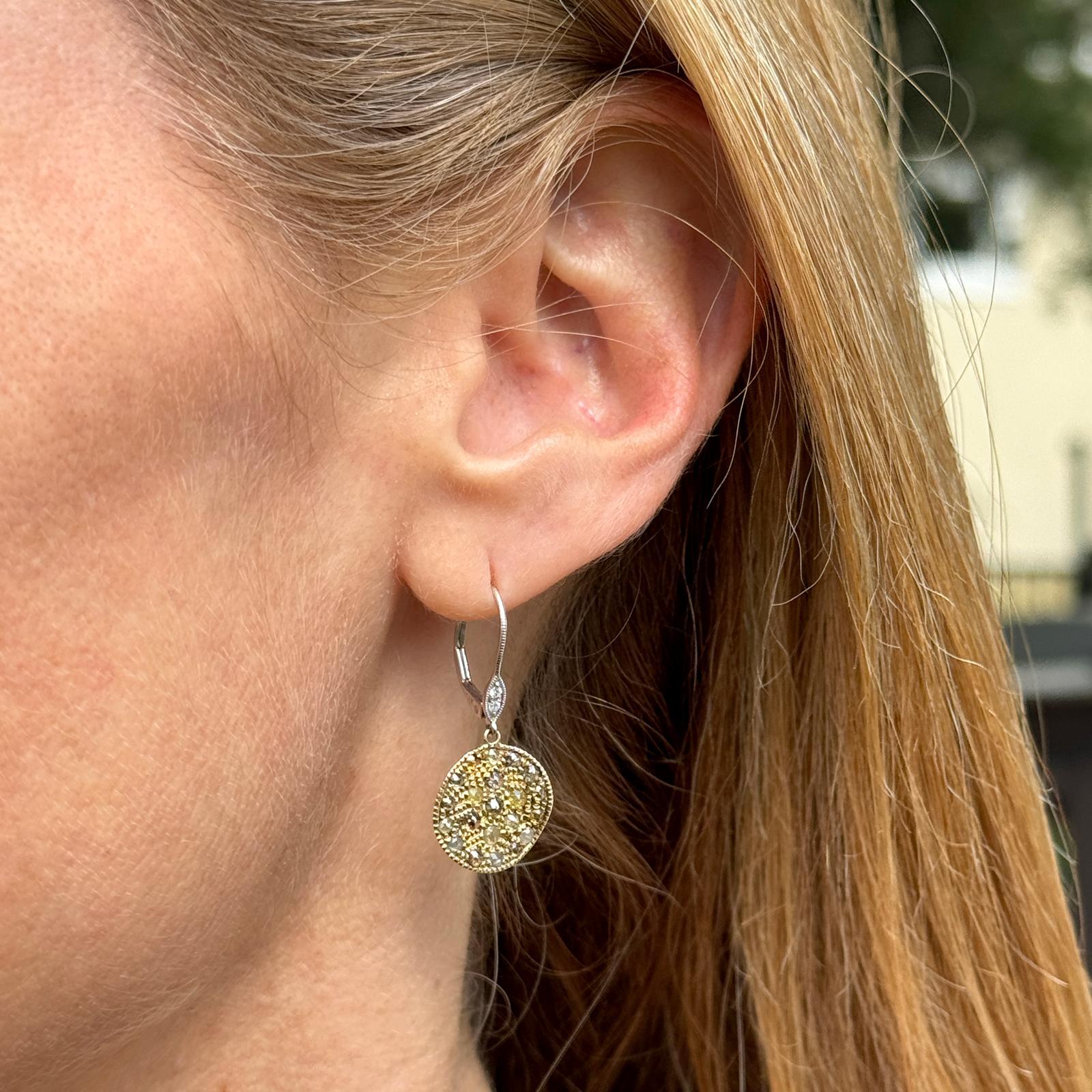 Diamond drop earrings by designer Meira T crafted in 14 karat yellow & white gold. The disc earrings feature mixed cut diamonds weighing approximately .50 carat total weight. The discs measure 14mm in diameter and 30mm in length. Weight: 3.4 grams.