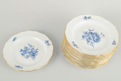 Meissen. 12 porcelain plates with blue floral motifs and gilt rim