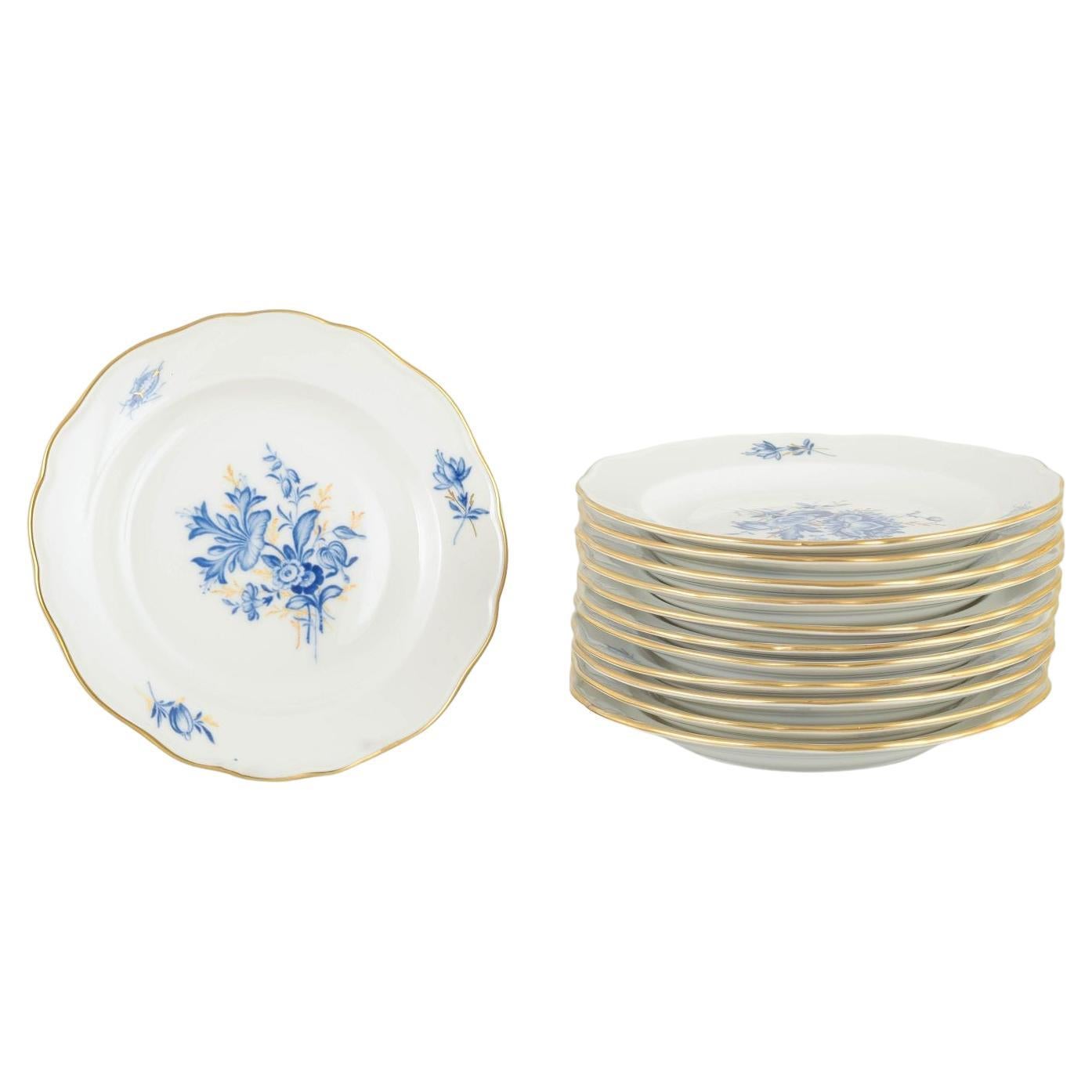 Meissen. 12 porcelain plates with blue floral motifs and gilt rim