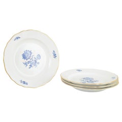 Meissen. 4 assiettes plates en porcelaine avec motifs floraux bleus et bordures dorées.