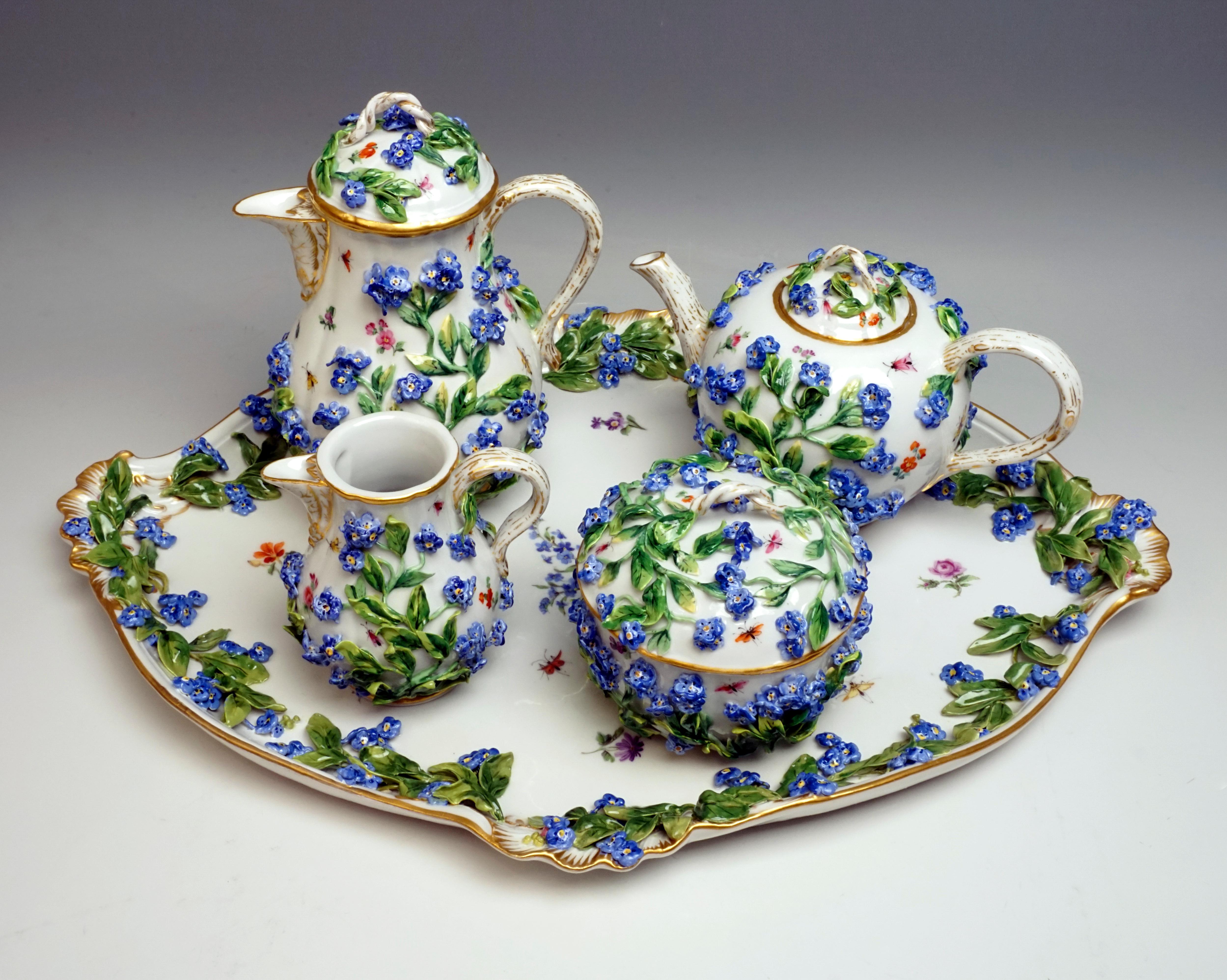 Meissen centerpiece consisting of coffee and teapot, milk jug, sugar bowl and serving plate. All parts are richly covered with sculptured forget-me-nots and painted with scattered flowers and insects, as well as decorated with