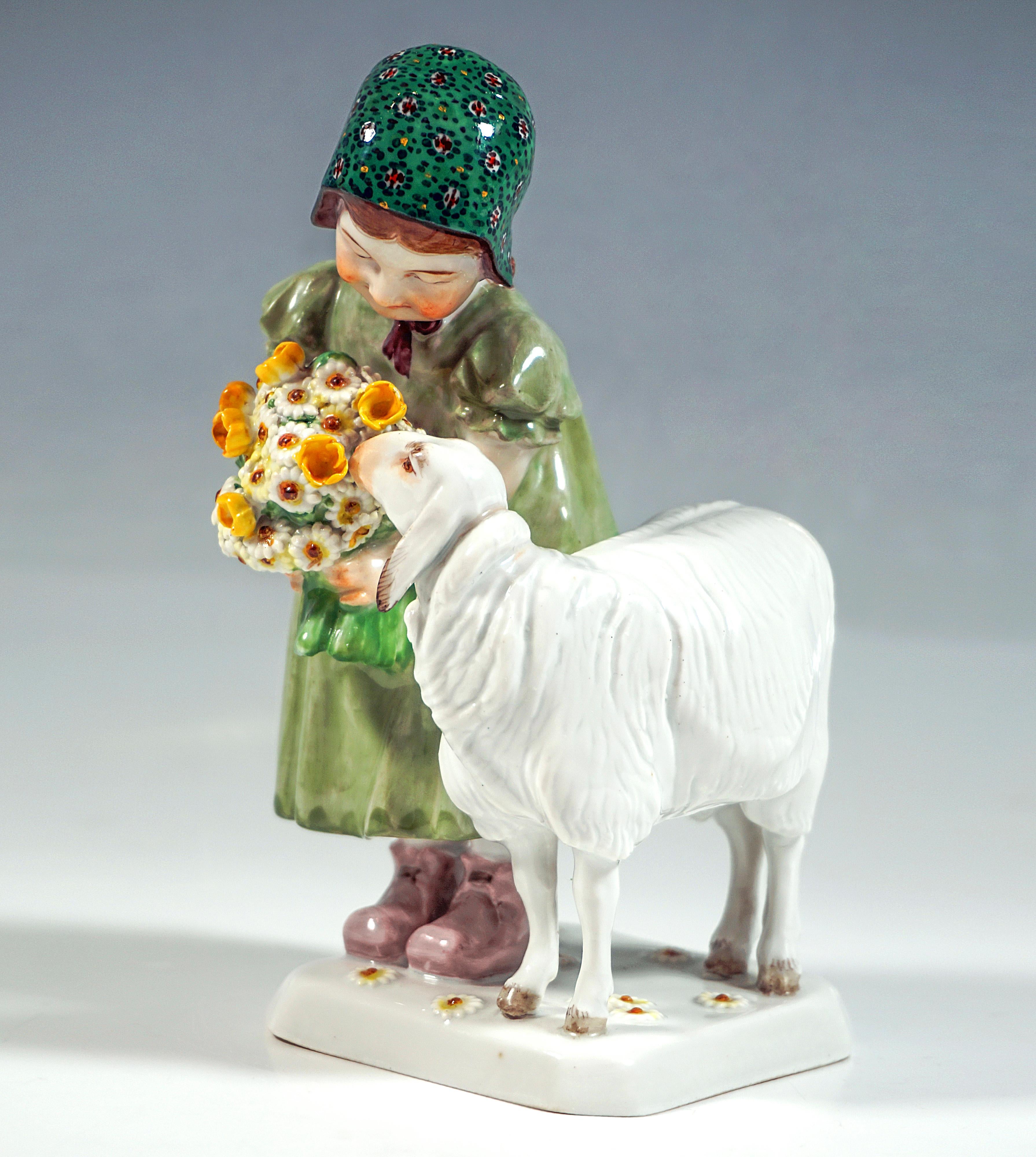 Very loving Art Nouveau Child Figure Group:
Girl in green dress and patterned cap holding a bouquet of flowers with both hands and leaning down to the sheep sniffing the flowers.
White square base with beveled corners and daisy decoration in
