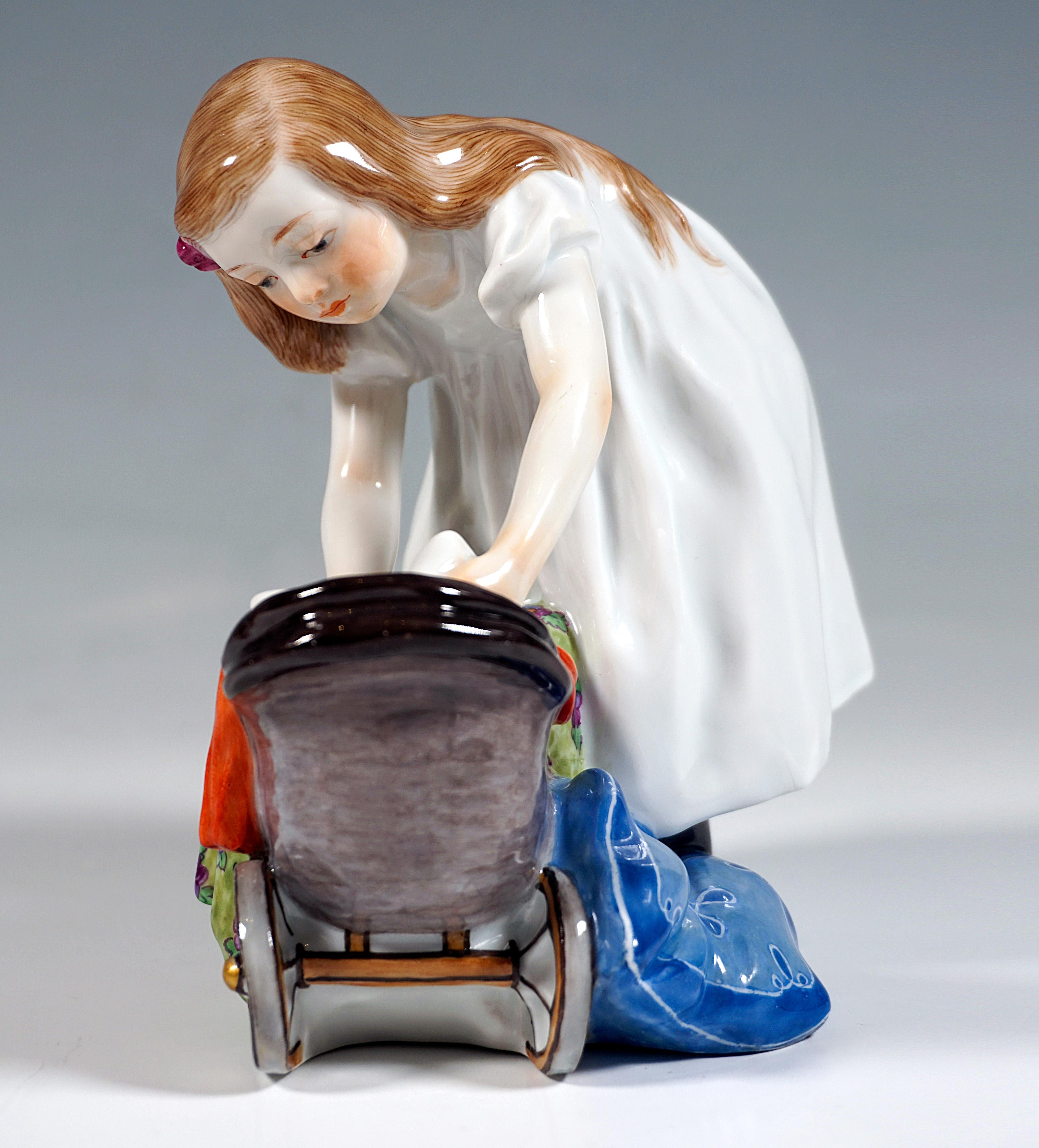 Art Nouveau Meissen porcelain figure from the time the model was created:
The girl in a white dress and with a blue bow in her long hair bends over the wicker doll's pram and places the doll into the deep pillow.
Modeling and painting of the finest
