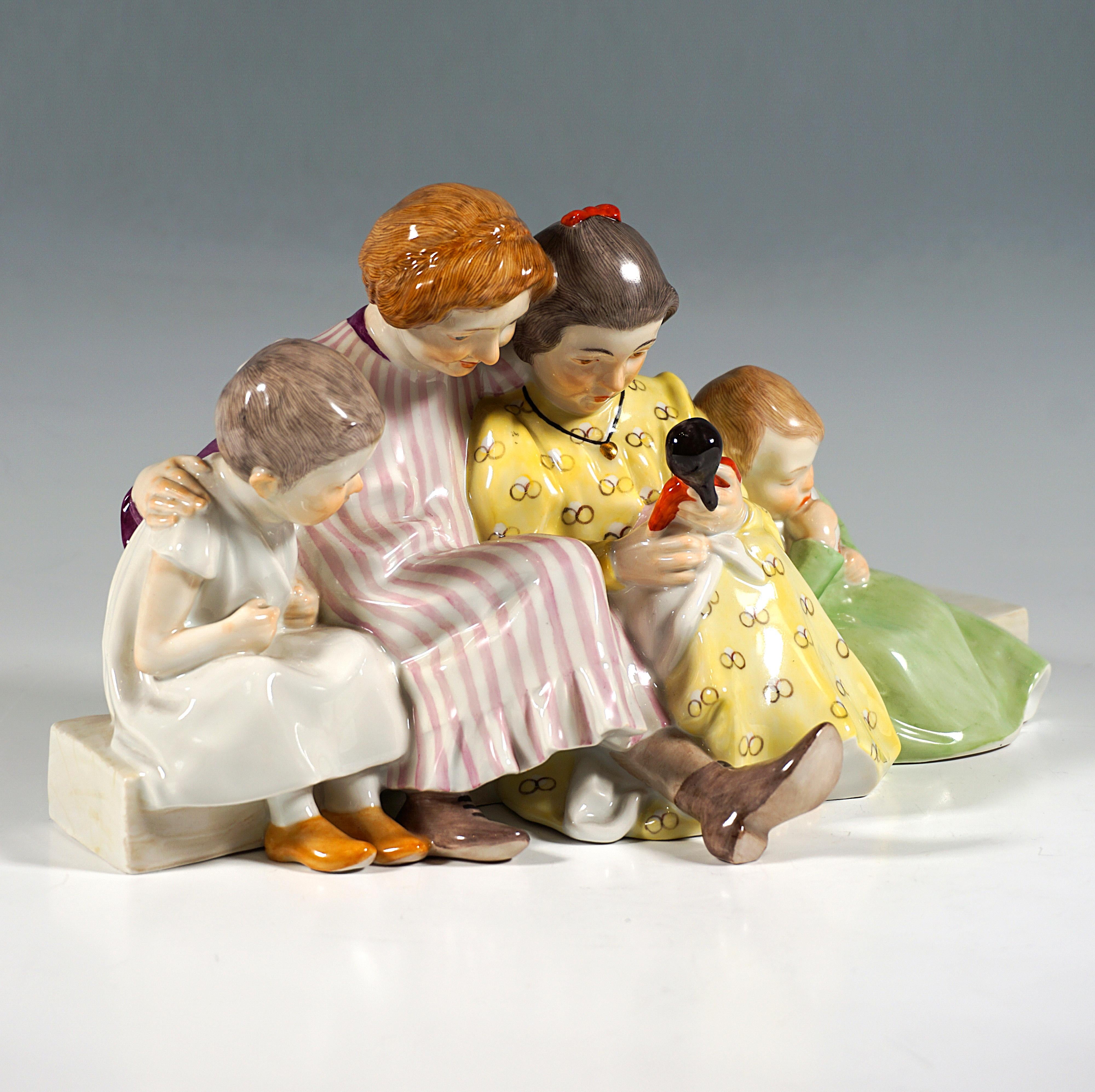 Finest Meissen porcelain figure group:
Two girls in patterned dresses with their hair tied up, flanked by two small children in long shirts, sitting on an elongated flat stone pedestal, one girl holding a doll on her lap, the two playmates on her