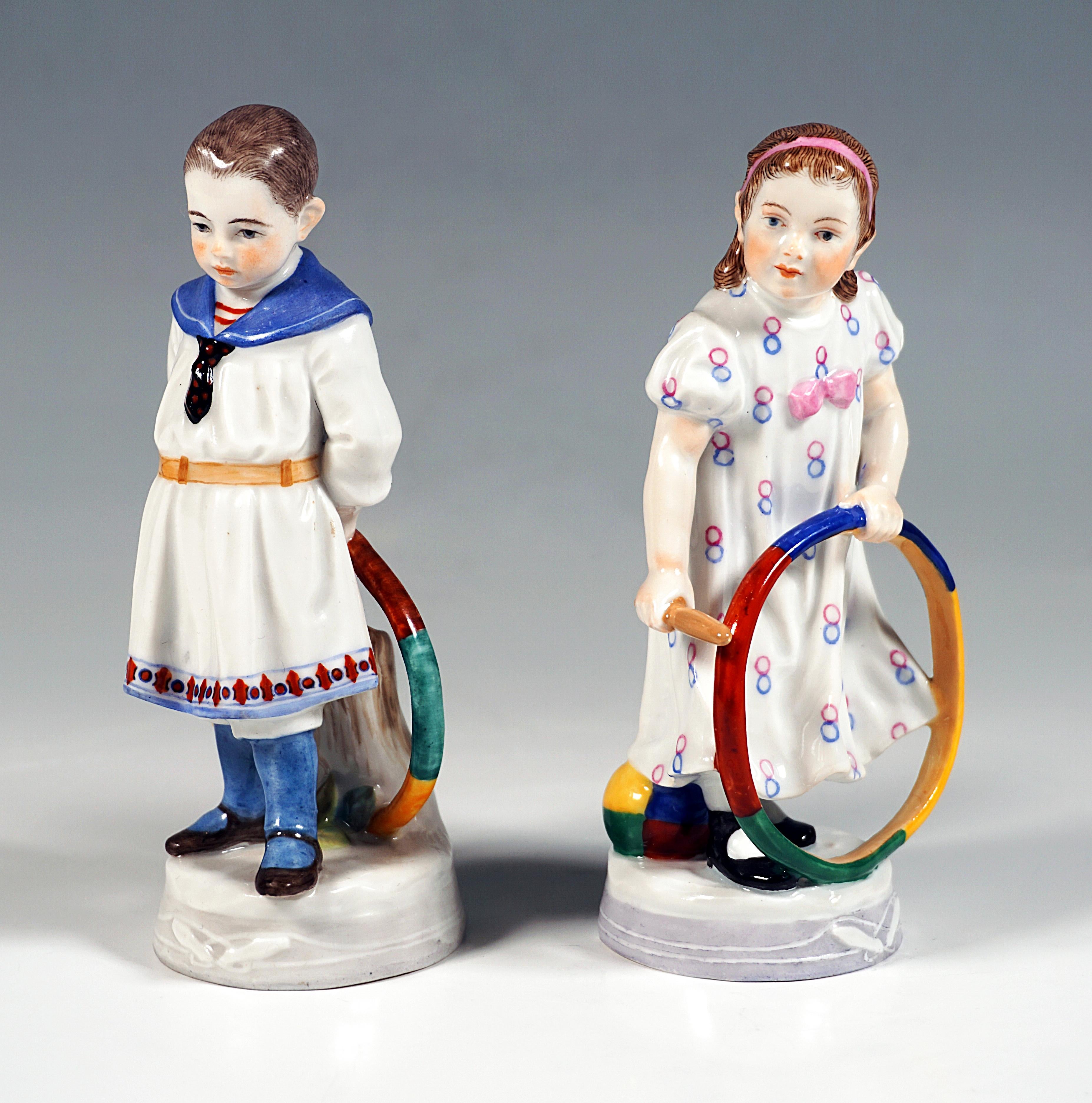 Very rare Meissen Art Nouveau porcelain figurines:
Two children with colorful hoops:
Standing boy in sailor dress, holding the hoop with both hands behind him standing on the ground, supported from behind by a tree trunk, the girl in a dress with a