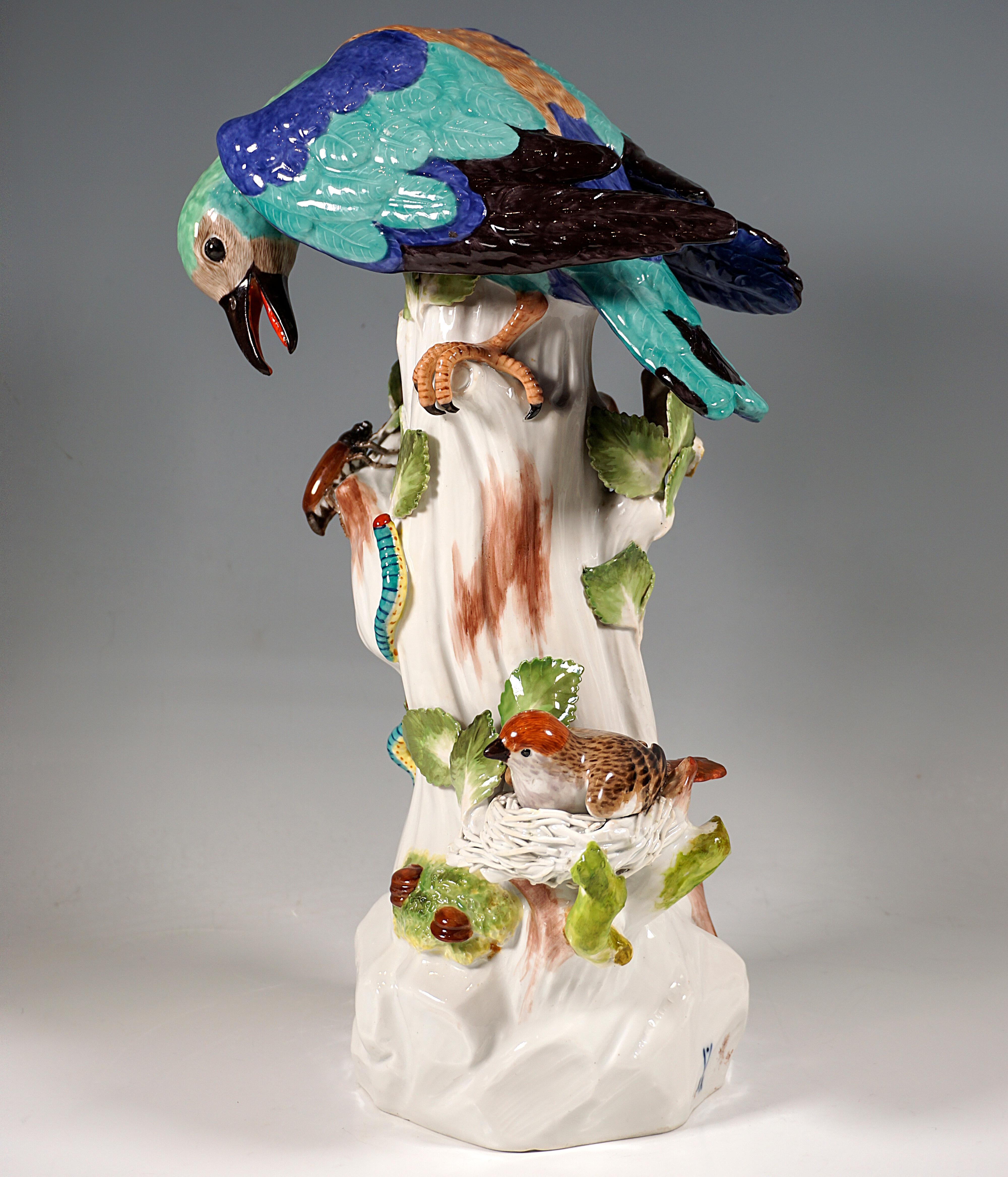 Very elaborate and lovingly designed group of animal figures:
European roller leaning forward, also known as almond crow in German-speaking countries, sitting on a tree trunk with open beak, below the bird a large beetle and caterpillars, its prime