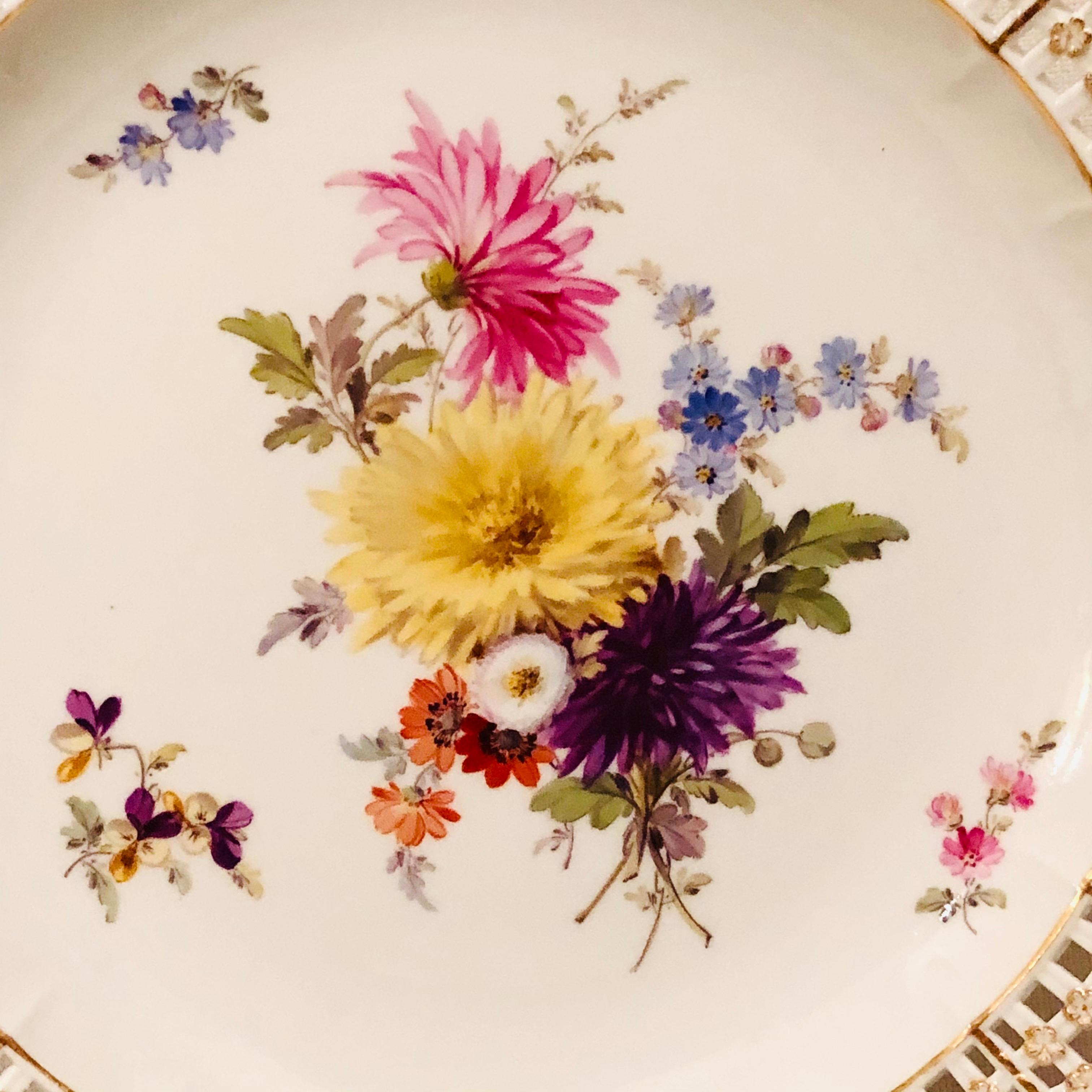 This is an exquisite Meissen cabinet plate painted with a large beautiful flower bouquet. The Meissen plate has a very intricate reticulated or open work border profusely decorated with raised gold and blue forget me nots. This Meissen plate is from