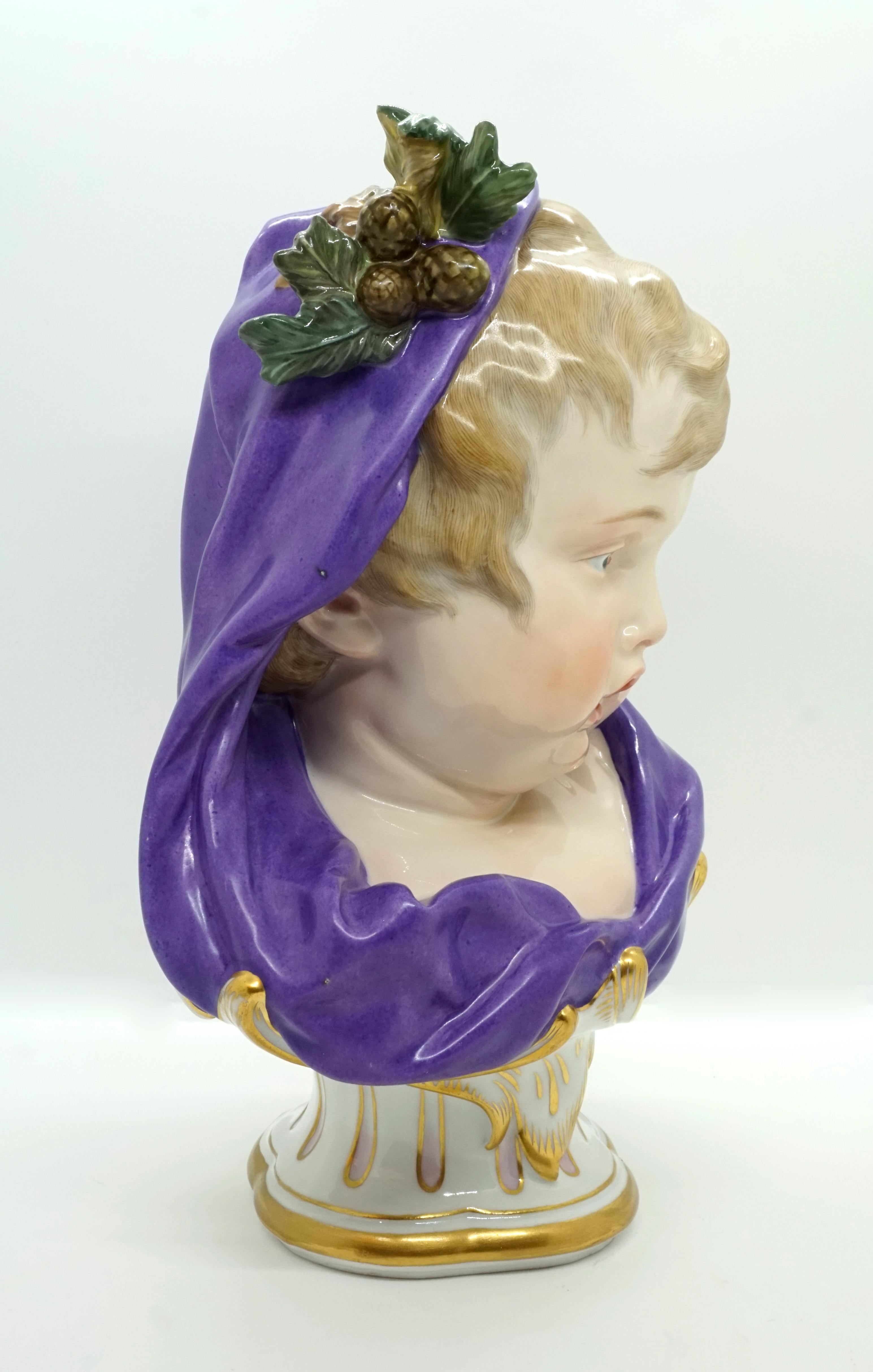 Bust of a boy with a purple cloak, which, like a hood, covers his blond curls, adorned with needle branches and cones.
On a matching curved base with a four-pass plan, rocailles and gold decoration.
Extremely loving design down to the smallest