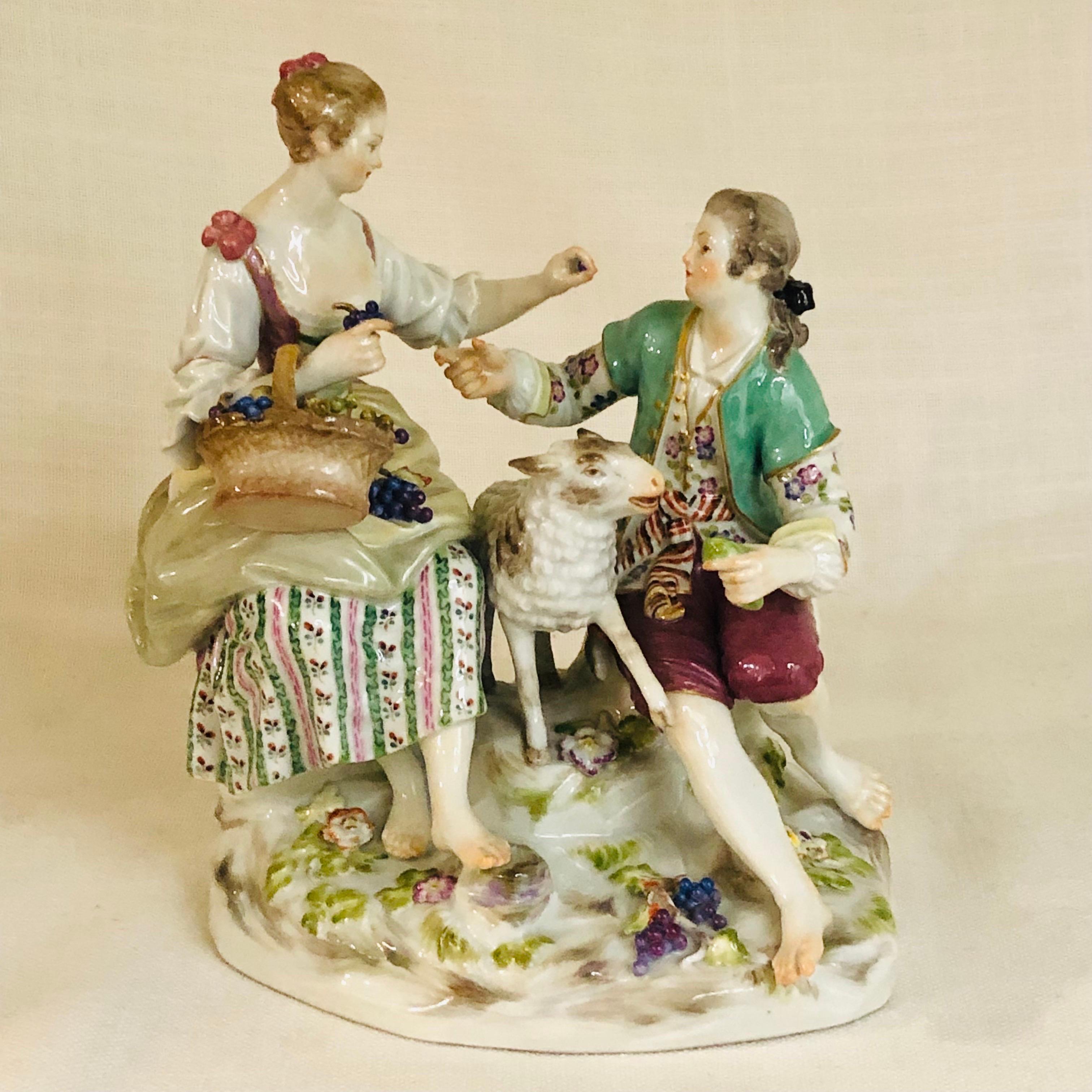 This is an enchanting Meissen figural group of a pastoral scene of a romantic couple in their garden with their lamb. The lady is feeding her lover grapes, while the man is feeding his lamb some greens. They are dressed in colorful summer attire
