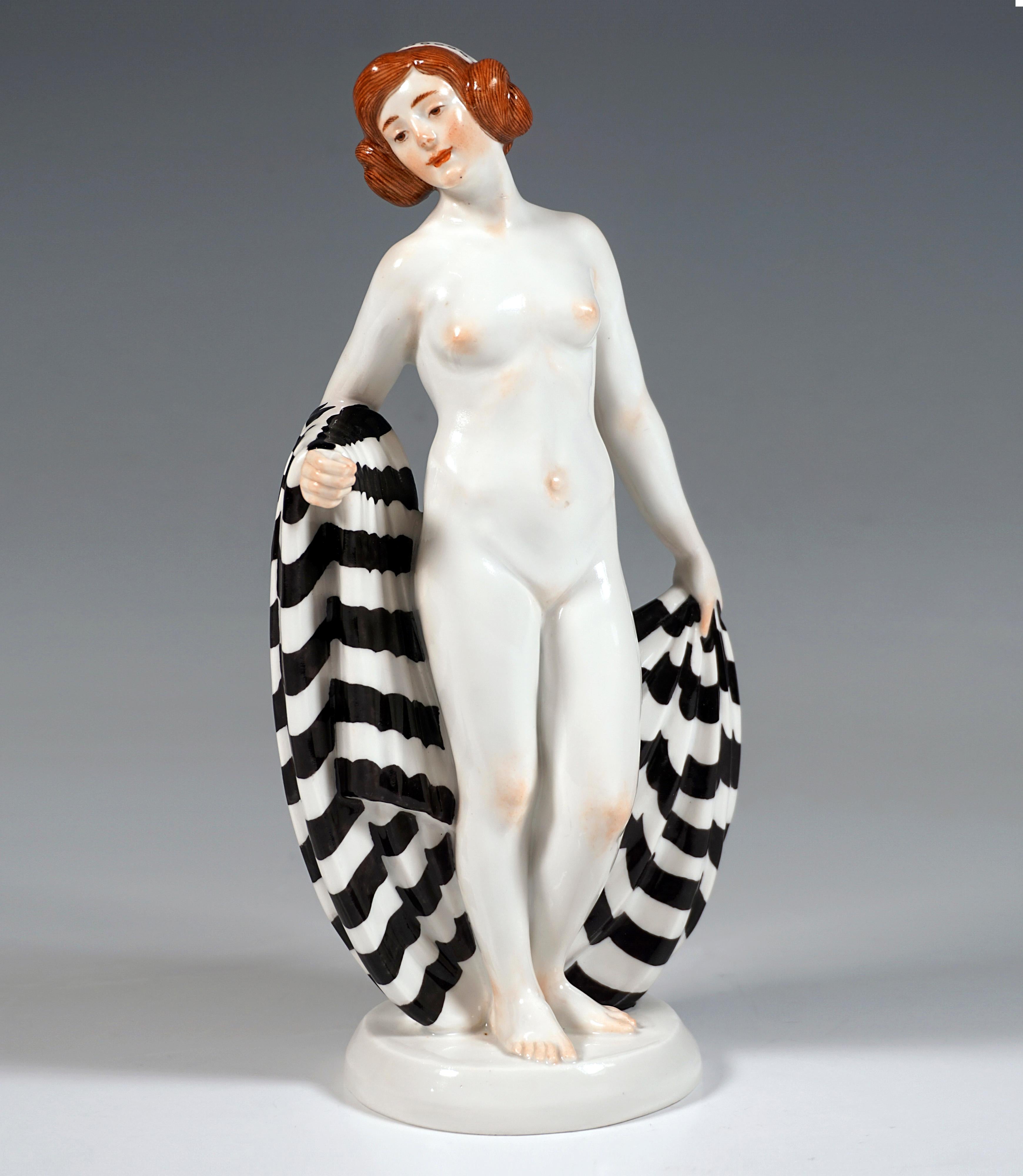 Depiction of a young unclothed Art Nouveau girl with artfully pinned up hair with incorporated hood, a large striped cloth wrapped around her right forearm and holding it behind her resting on the ground with her left hand.
On round flat base with