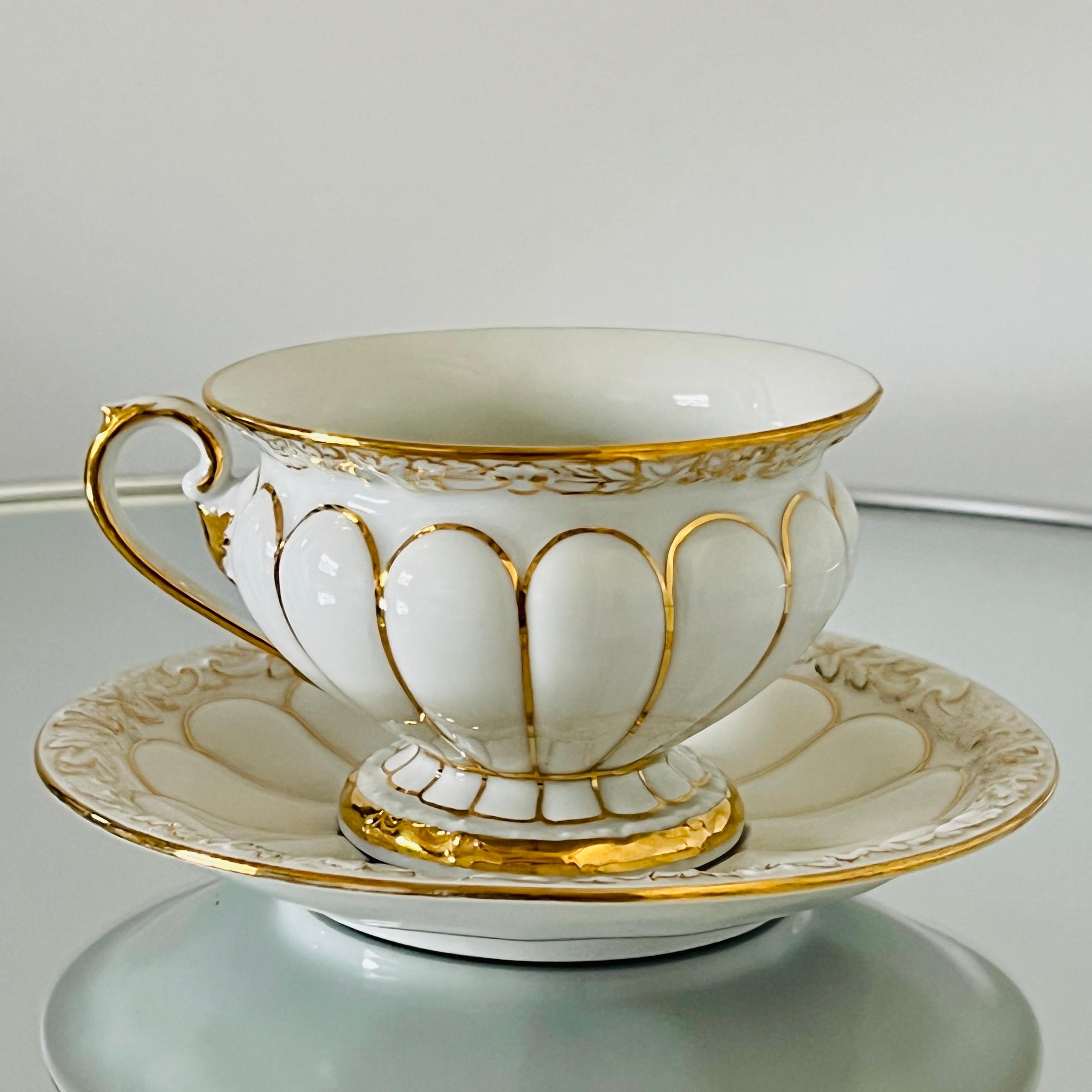 Ensemble de 13 tasses et soucoupes en porcelaine de Meissen de la série opulente Golden Baroque, fabriquées à la main en Allemagne. Les tasses et les soucoupes ont une finition en glaçure blanche avec des motifs ornementaux en relief représentant