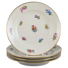 Meissen, Germania, quattro piatti con motivi floreali policromi, bordo dorato.