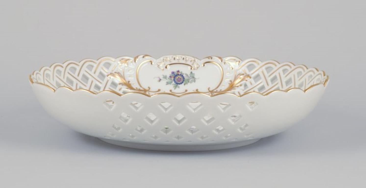 Meissen, Germany. Open lace bowl in porcelain, decorated in gold with an exotic bird on a flower branch. Hand-painted.
Mid-20th century.
Marked.
First factory quality.
In perfect condition.
Dimensions: 21.5 cm x Height 4.5 cm.