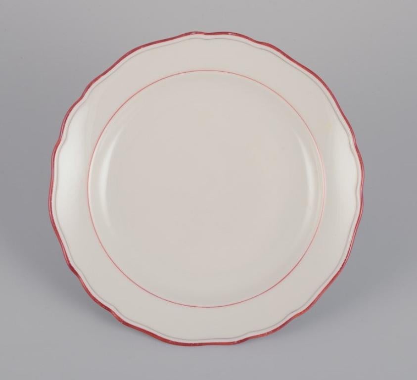 Meissen, Alemania. Un juego de diez platos de porcelana. 
Decorado con ribete rojo coral. Art Déco.
Ca. 1930s.
Marcado.
Tercera calidad de fábrica.
Perfecto estado.
Dimensiones: D 17,5 cm.