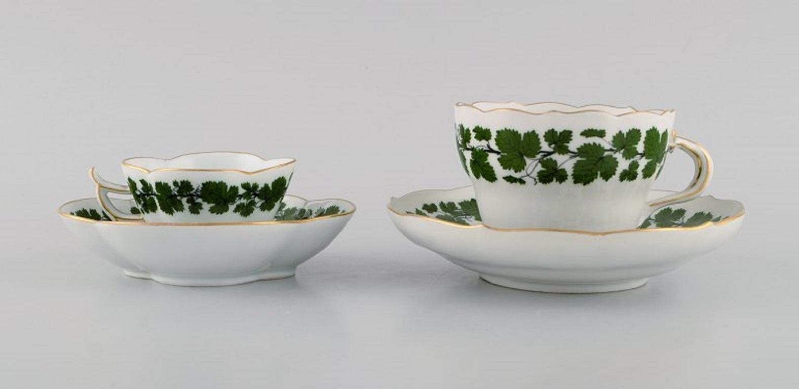 Taza de moka y té Meissen Green Ivy Vine Leaf de porcelana pintada a mano con borde dorado. 
Años 20 / 30.
La taza de té mide 9 x 6,5 cm.
Diámetro del platillo: 14.8 cm.
La taza de moca mide 7 x 4,5 cm.
Diámetro del platillo: 12.3 cm.
En