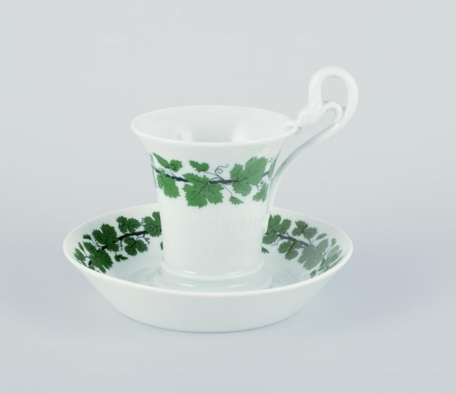 Meissen, Green Ivy Vine, two coffee cups with tall handles shaped like swans. With saucers.
Mid-20th century.
Marked.
Perfect condition.
First factory quality.
Saucers in third factory quality.
Cup: Diameter 7.7 cm. without handle x Height 9.9 cm.