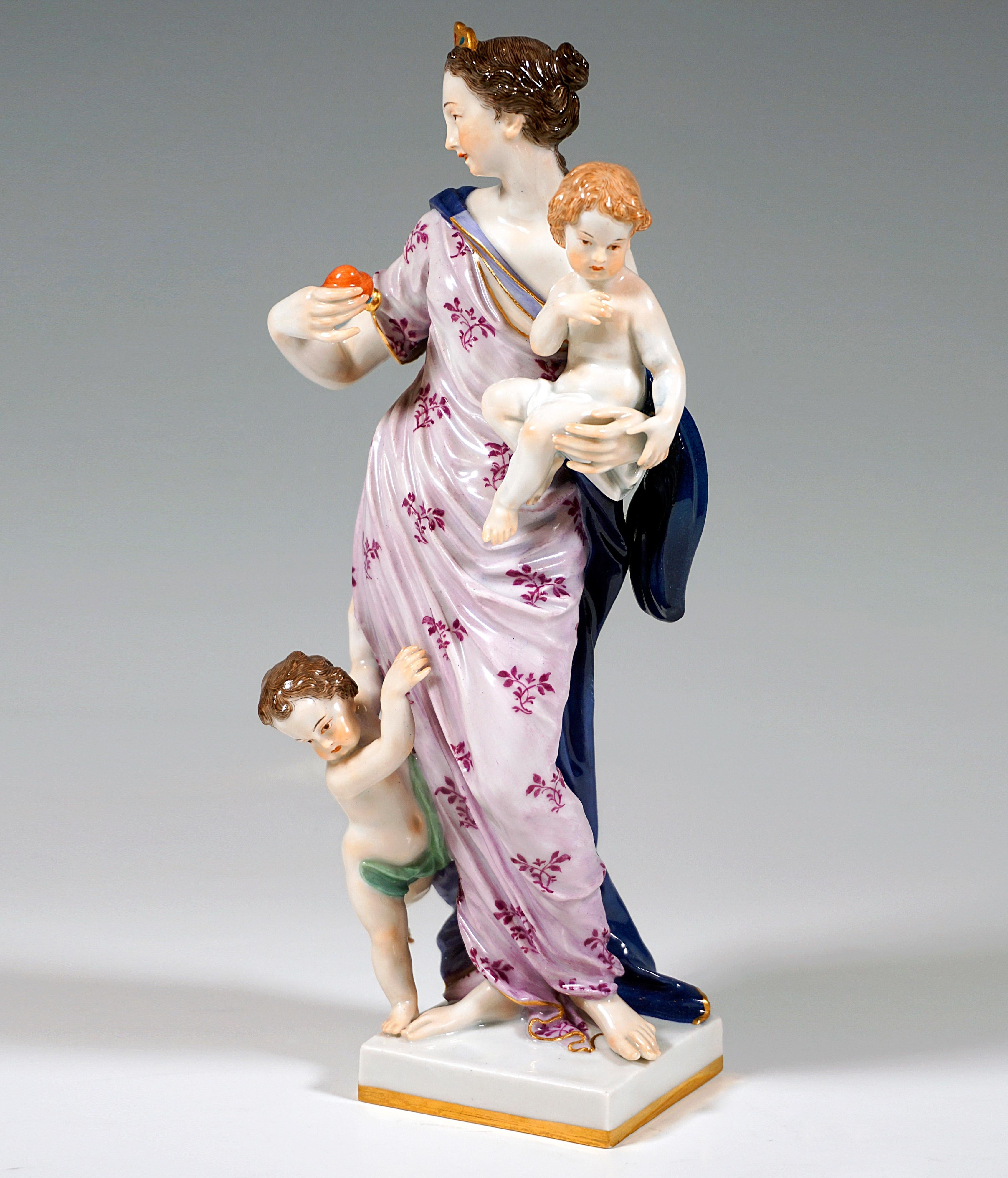 Very rare and exceptional porcelain figure group:
Standing young beauty with her hair tied back at the nape of her neck and crowned with a tiara, wearing a long dress softly embracing her body and a blue cloak reaching down to the ground, carrying