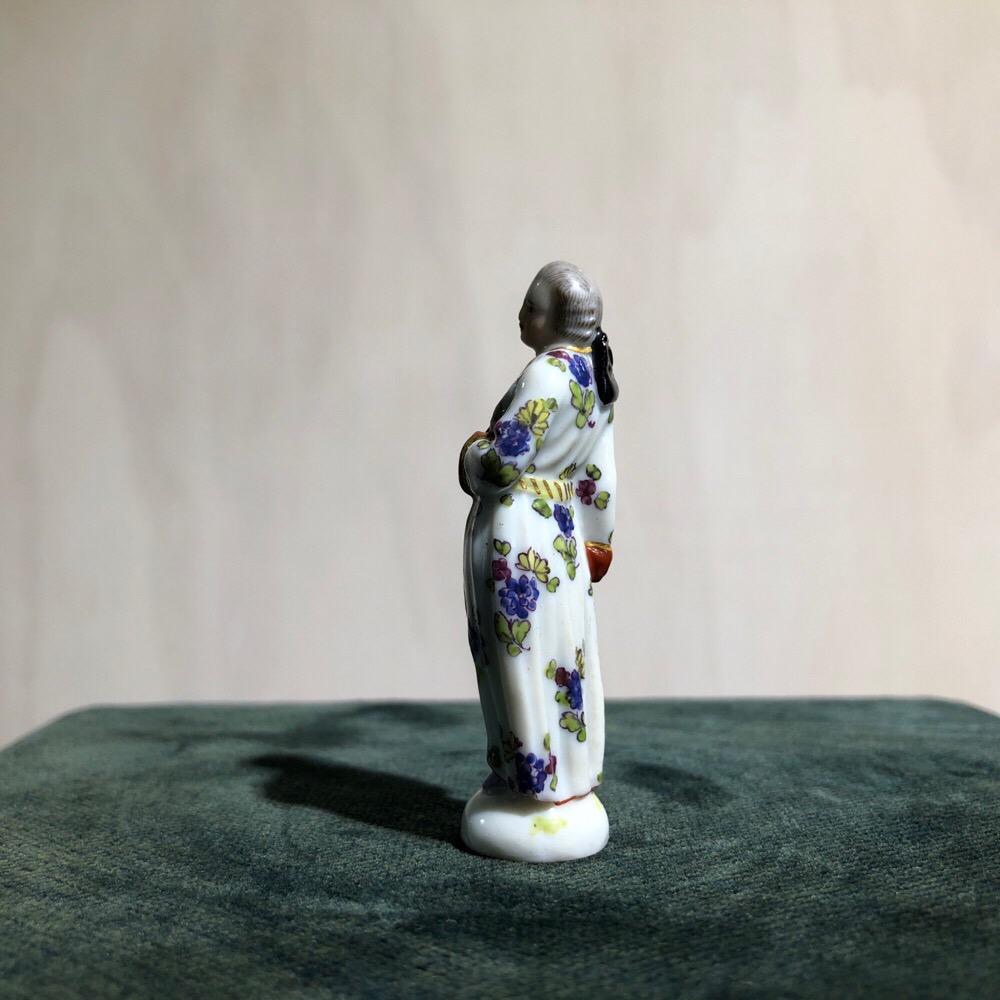 Rare Meissen pipe stopper (flohbein), modelled as a man in a flower decorated gown, holding a pipe,
circa 1750

A rarely seen small scale Meissen figure, made to use to compact tobacco in a pipe. As the figure is dressed in a smoking jacket and