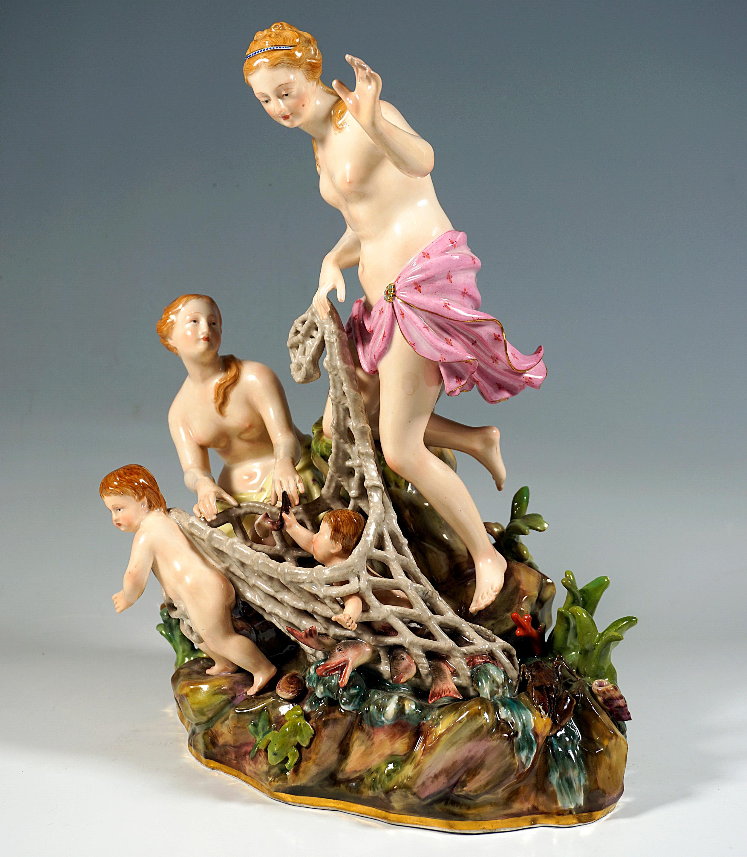 Very elaborate and lovingly designed group of figures: two women kneeling on a rock, using a putto to pull the small triton caught in a net ashore, very detailed rock base with various plants and animals: reeds, a frog, various shells, a crayfish,