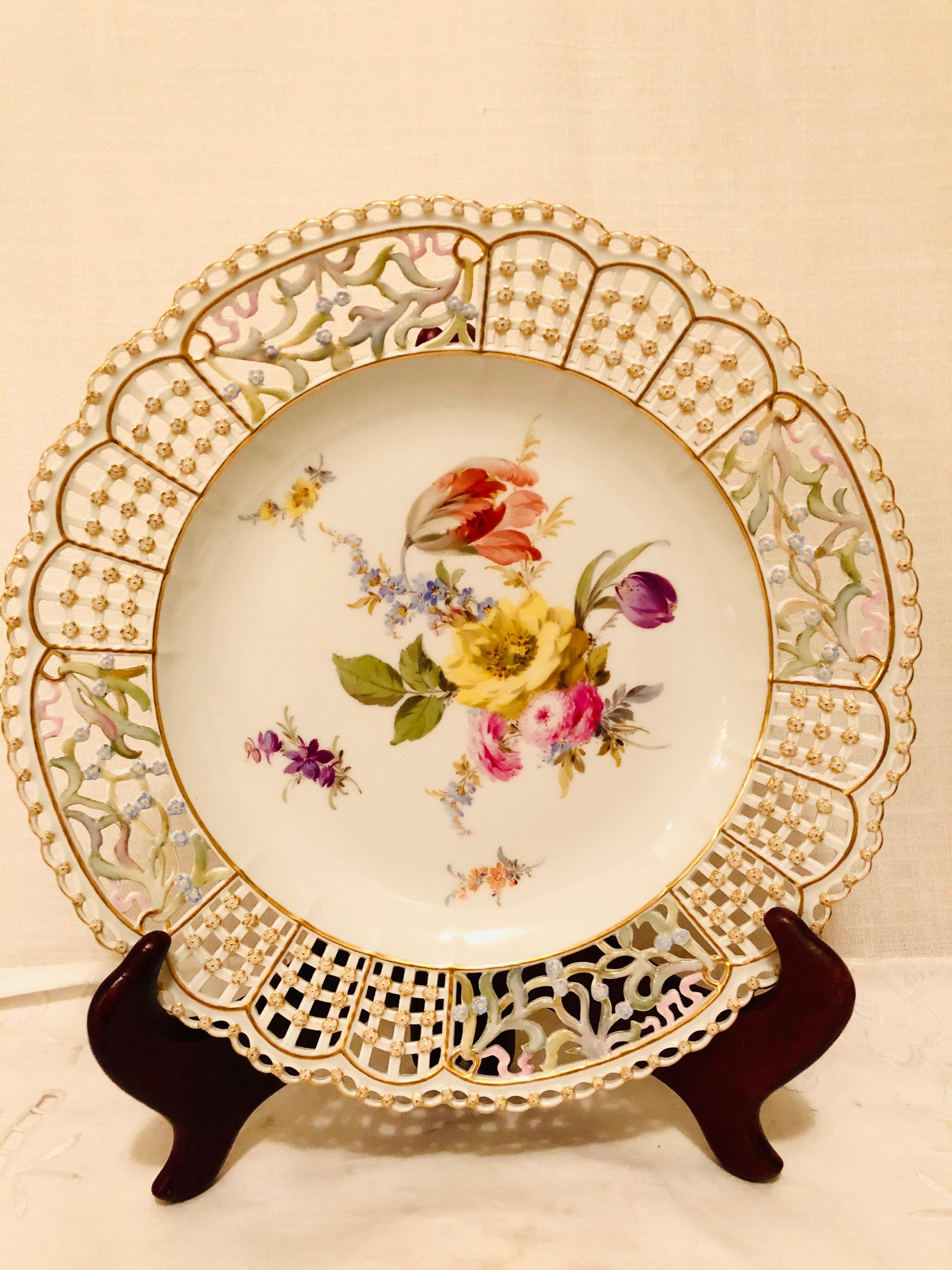 This is an exquisite Meissen cabinet plate painted with a large beautiful flower bouquet with a large tulip and other flowers. The Meissen plate has a very intricate reticulated or open work border profusely decorated with raised gold and blue