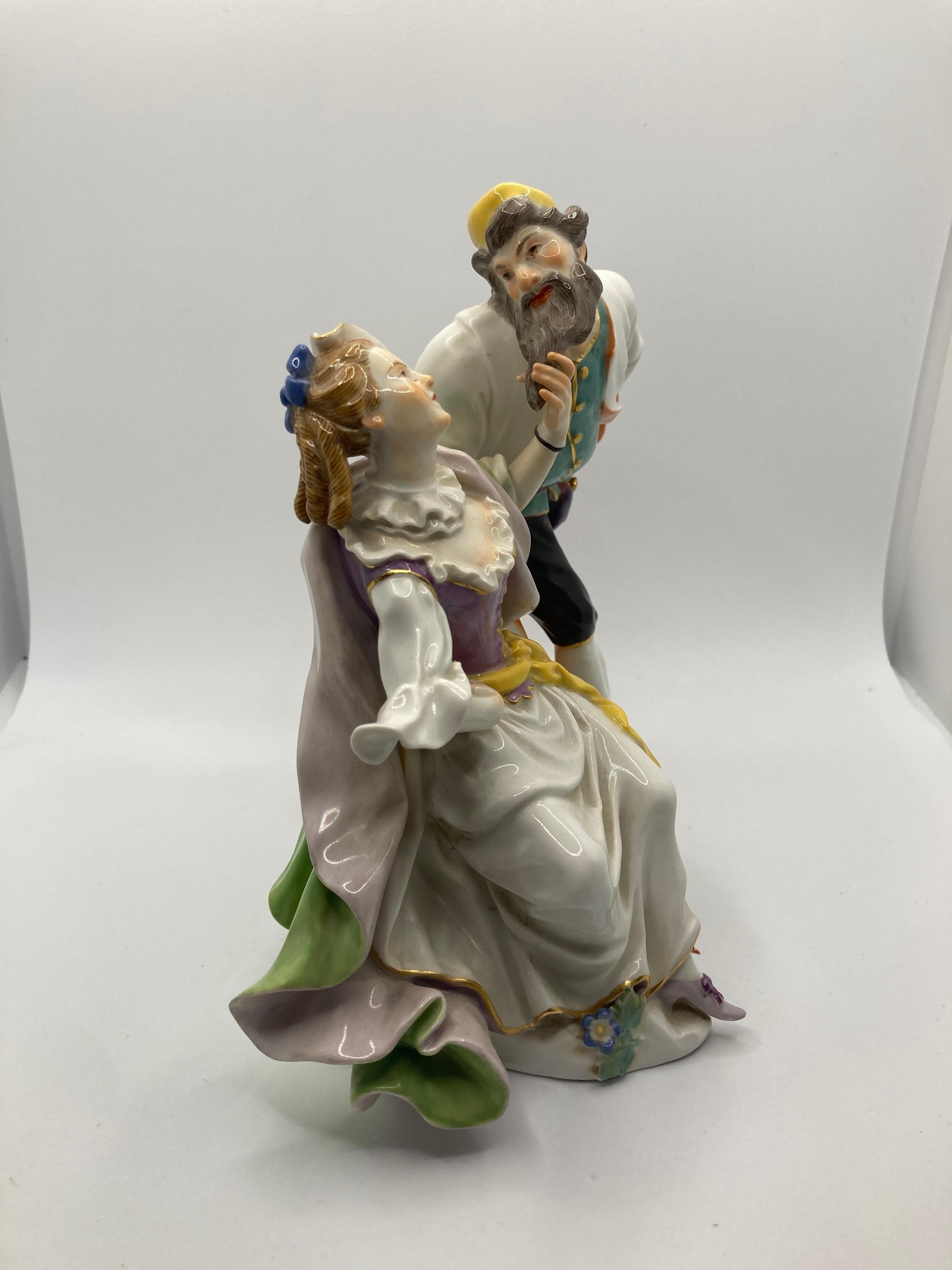 Meissen figure group of 'Pantalone and Columbine' 

Columbine seated holding a mask under her right arm, wearing a pink-lined green cloak and Pantalone in a salmon pink-lined cloak, a turquoise waistcoat incised with scrolls and blue breeches, each