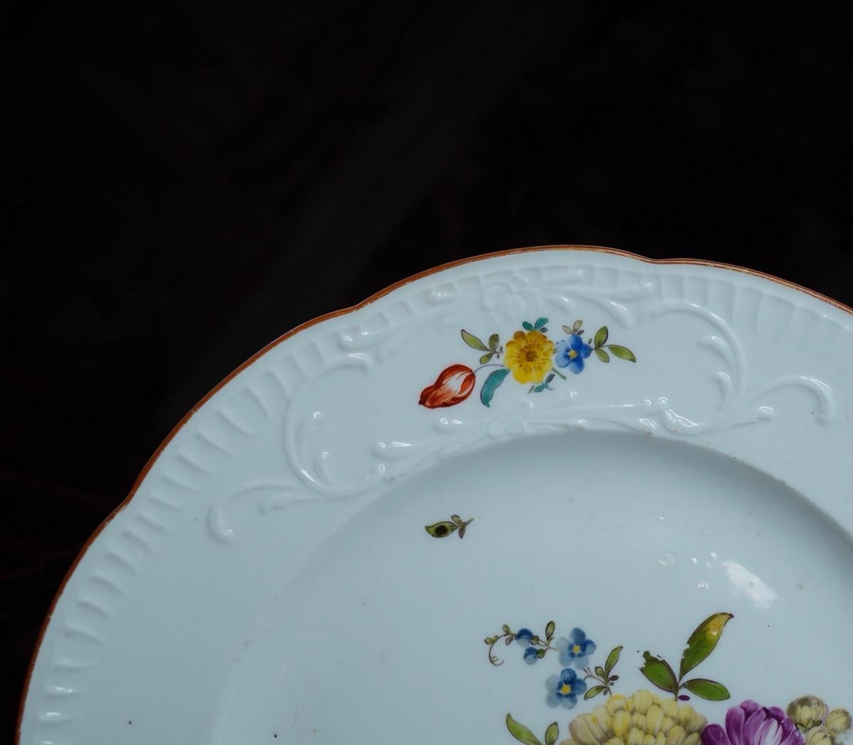 Meissen dinner plate of 'New Spanish' with scroll moulded rim, feathering to the edge, brightly painted with flowers within the three reserves, a larger spray to the center, the rim in pale brown.
Crossed swords & '.' mark,
circa 1760.