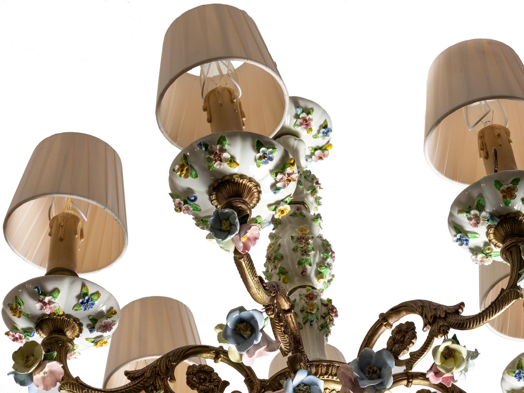 A Meissen styled white porcelain and bronze chandelier with six intricate bronze arms and hand-painted porcelain floral details in pink, blue, yellow and green details etched in the whitre porcelain and pink, blue, yellow and green petails ornating
