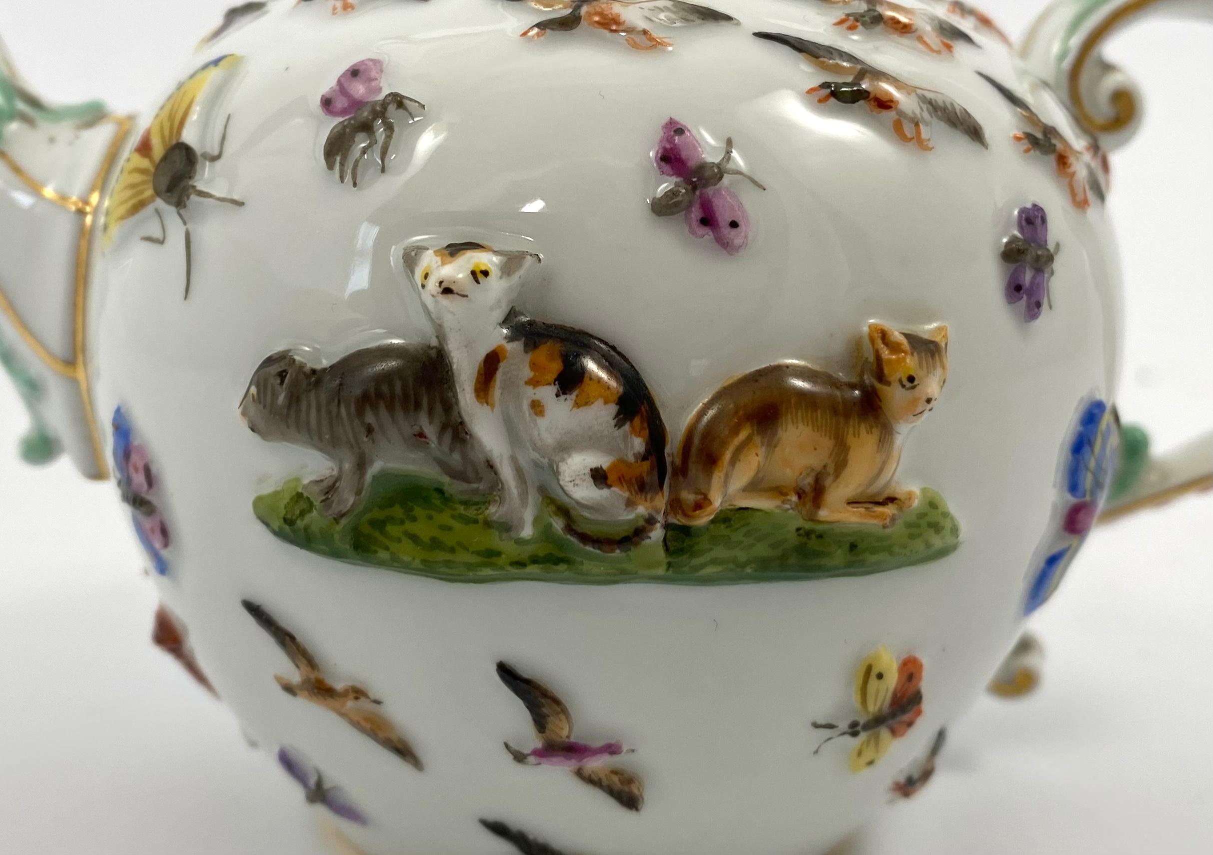 An extraordinary Meissen porcelain teapot and cover, c. 1830. The globular body, moulded to one side, with a group of three cats, on a grassy mound; the other side, with a St. Bernard. A squirrel sits beneath the spout, eating a nut, whilst a parrot