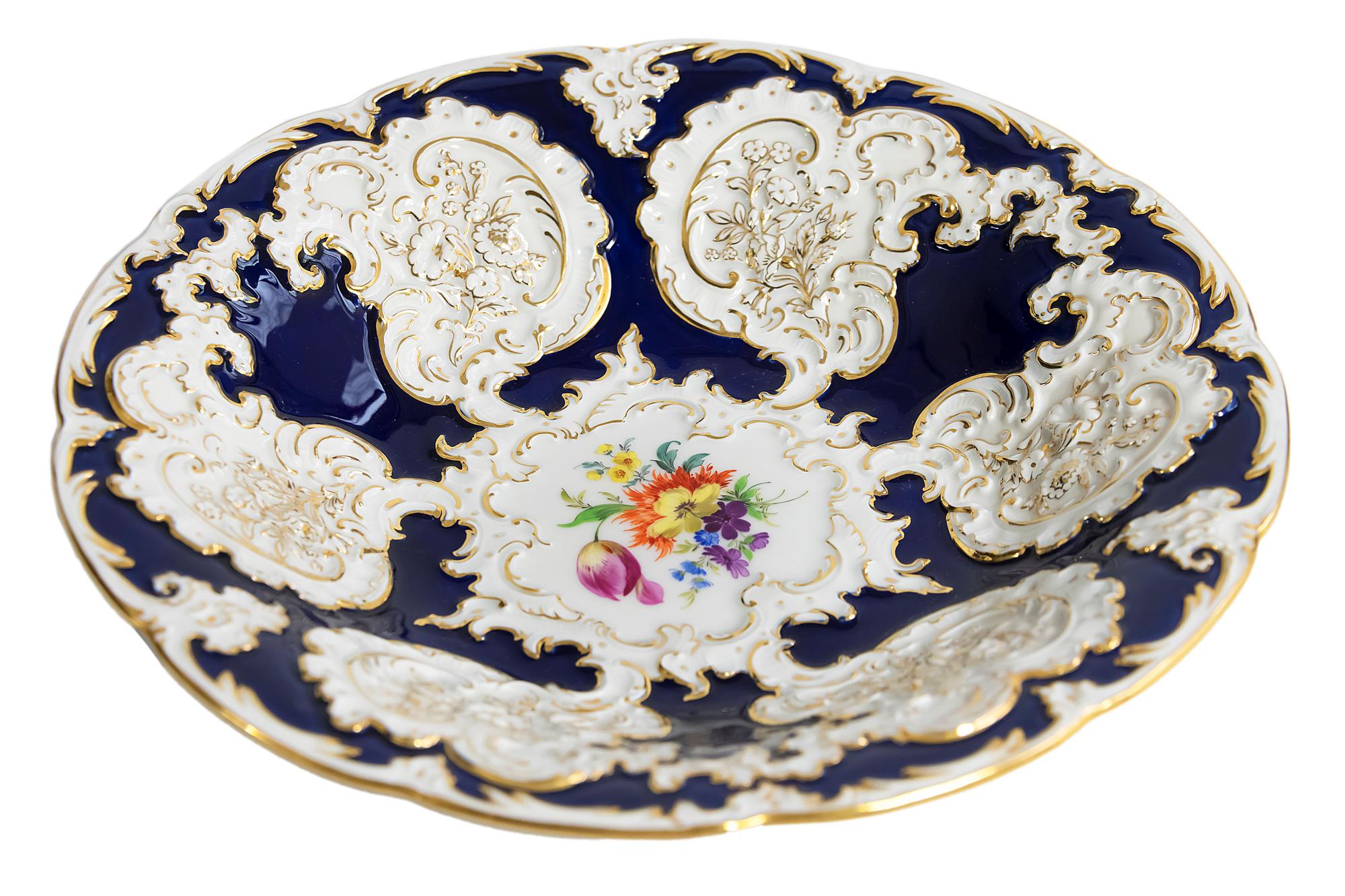 Meissen porcelain deep cabinet plate/bowl is cobalt blue color with gold decor and relief floral motives. It is hand painted with floral motives in the center.