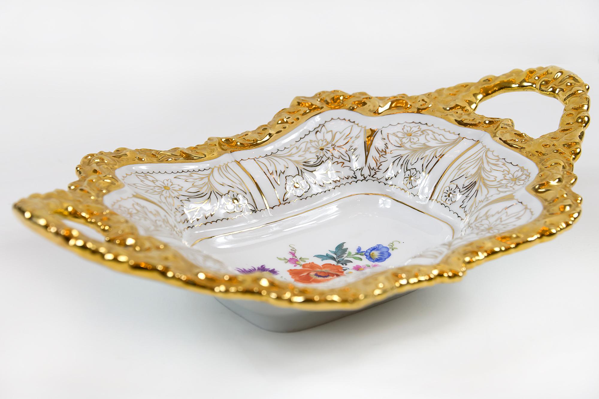 Meissen Porcelain deep cabinet plate or bowl with handles. This piece is hand painted with floral motive in the center and richly decorated gold edge.