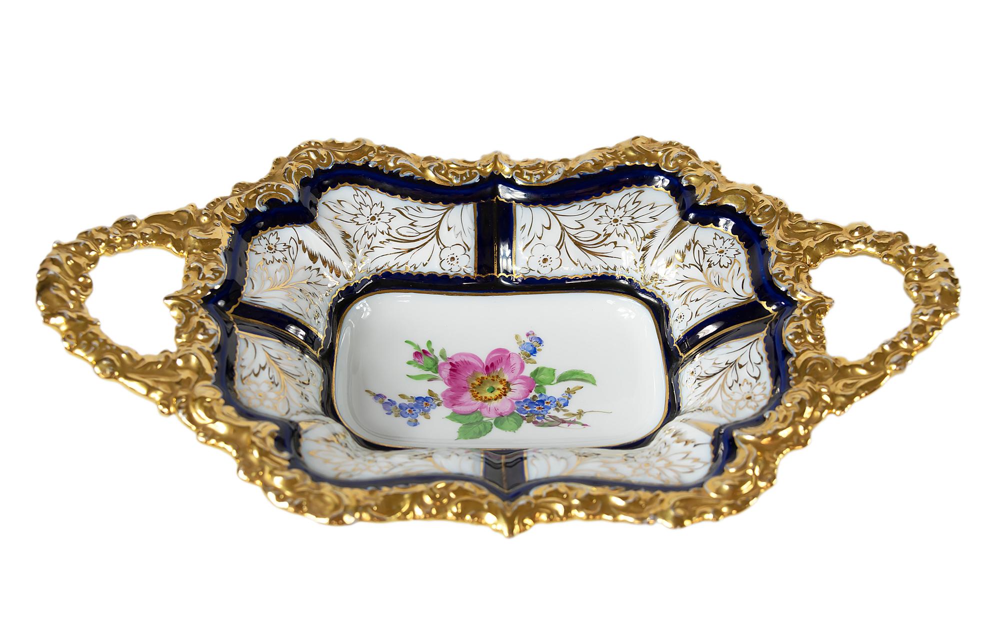 Meissen Porcelain deep cabinet plate with handles. This piece is hand painted in cobalt blue with floral motive in the center and richly decorated gold edge.
Signed on the bottom.