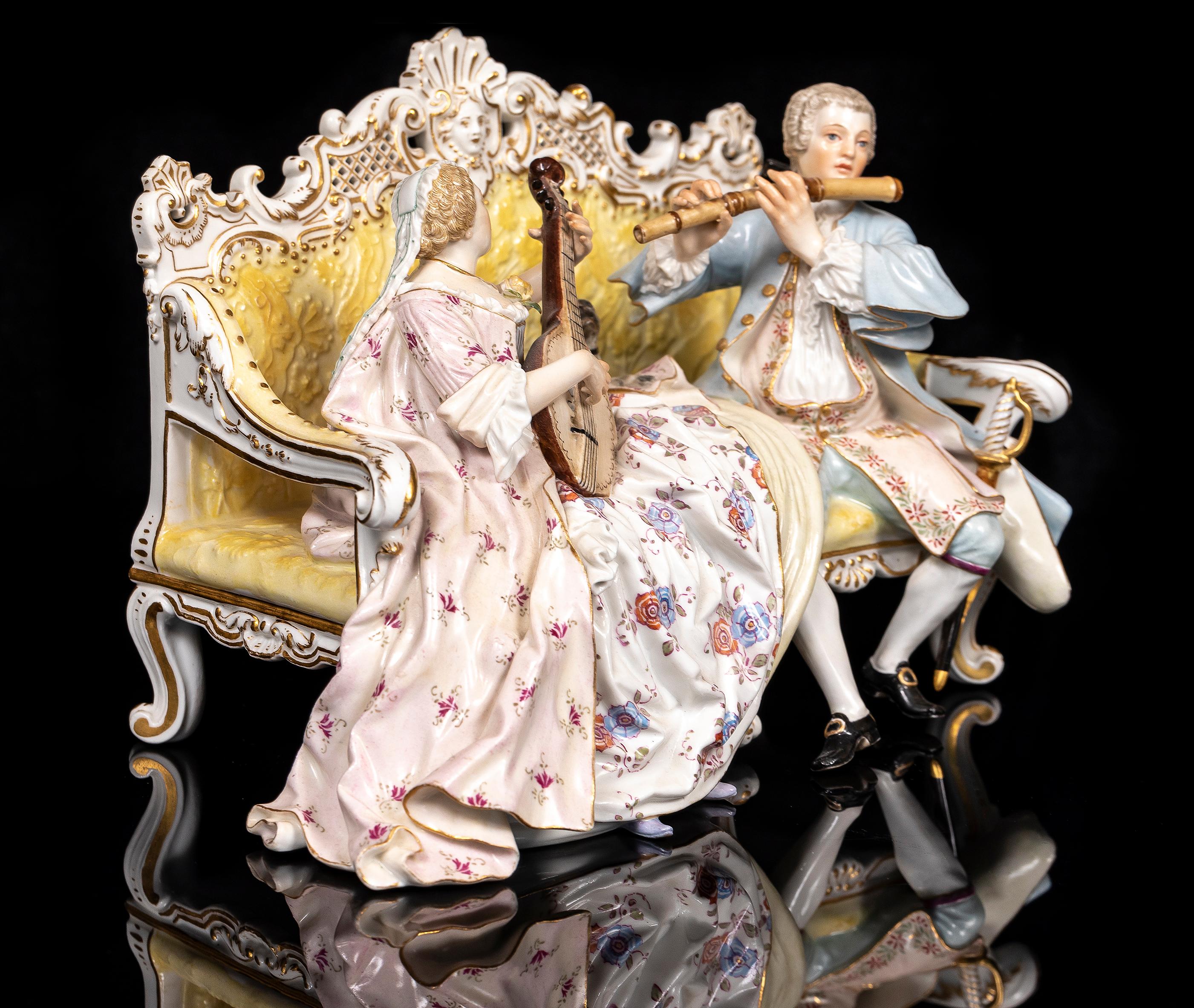 Meissener Porzellanfigurengruppe des 19. Jh.: Musikalisches Liebespaar auf einem Sofa sitzend mit Mops, nach J.J. Kandler.  Das Stück zeigt einen Mann und eine Frau, die auf einem verzierten Sofa sitzen und jeweils eine musikalische Darbietung