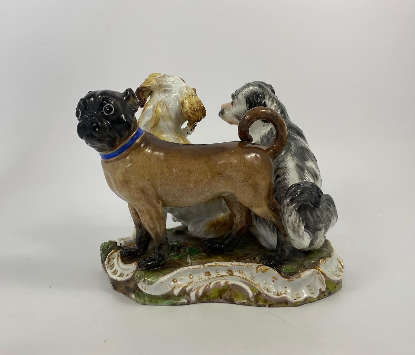 Meissen porcelain figure group of dogs, c. 1870. Modelled after Kaendler, the group is finely modelled as two Bolognese Spaniels, and a pug dog, set upon a shaped grassy mound base, edged in moulded rocaille, heightened in gilt.
The dogs are