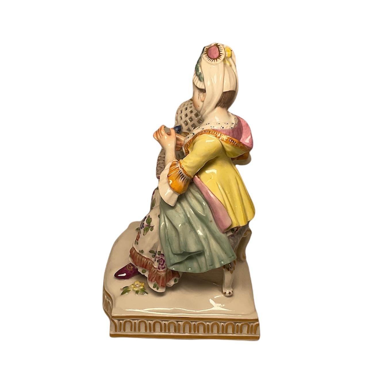 Dies ist ein Meissener Porzellan Dame Figurine, dass es Teil der Gruppe von fünf, die die fünf Sinne darstellt ist. Sie repräsentiert den Sinn für Berührung. Es zeigt eine Dame aus dem 18. Jahrhundert in einem Stuhl neben einem Beistelltisch mit