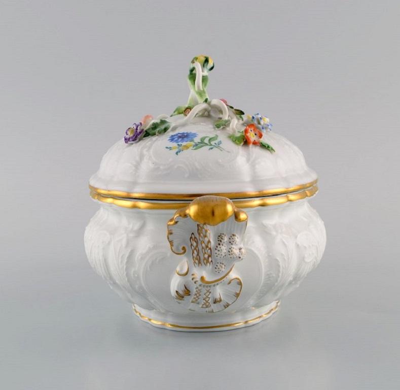 Meissen porcelain lidded tureen with hand-painted flowers and gold edge. 
Lid modelled with flowers and foliage. 1920s.
Measures: 22 x 13 x 13 cm.
In excellent condition.
Stamped.
2nd factory quality.