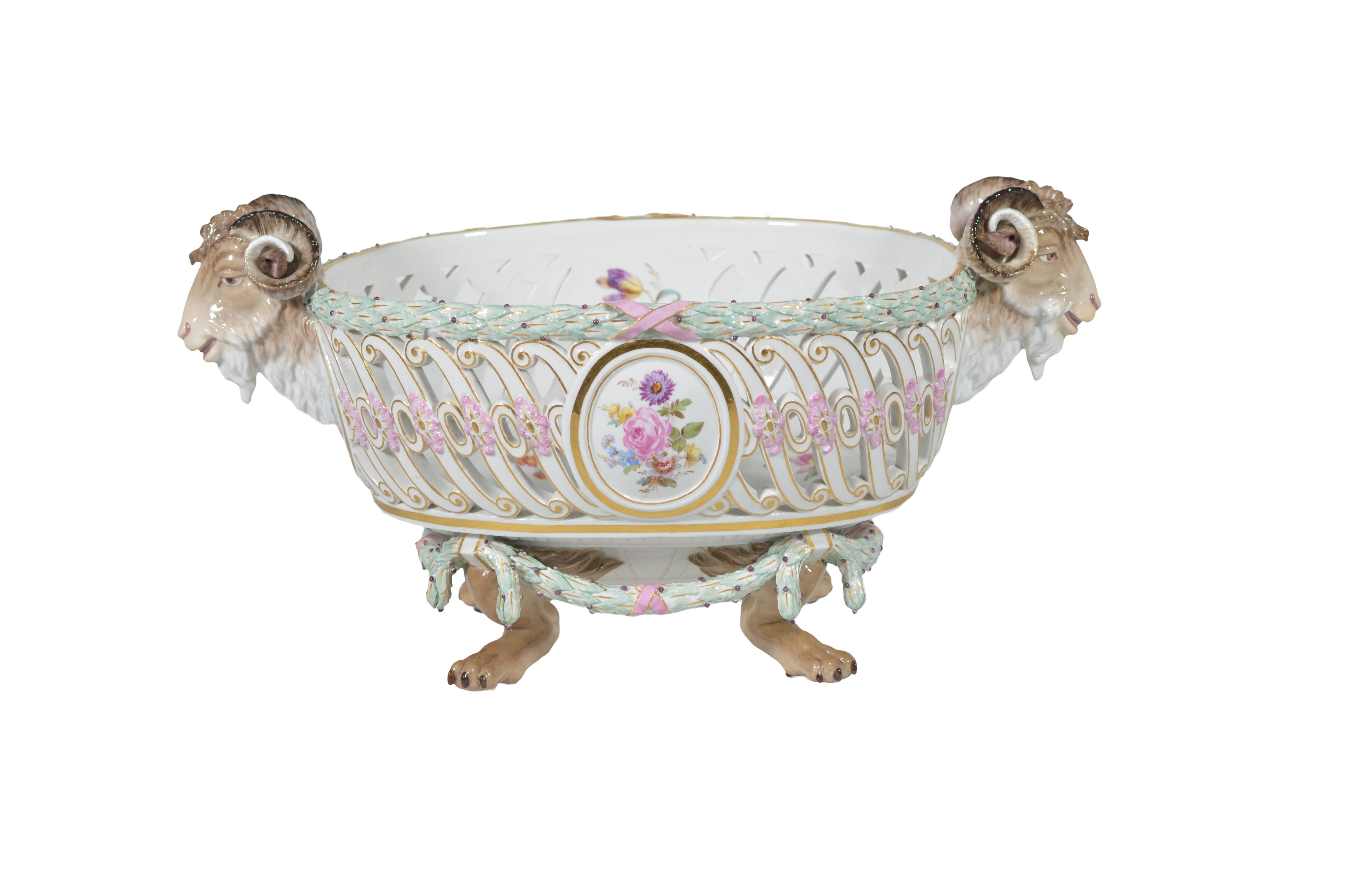 Precioso e inusual centro de mesa de porcelana reticulada de Meissen con asas en forma de cabeza de carnero, patas de león y borde en forma de corona.  La pieza central está formada por un cuenco circular reticulado elevado sobre cuatro patas. La