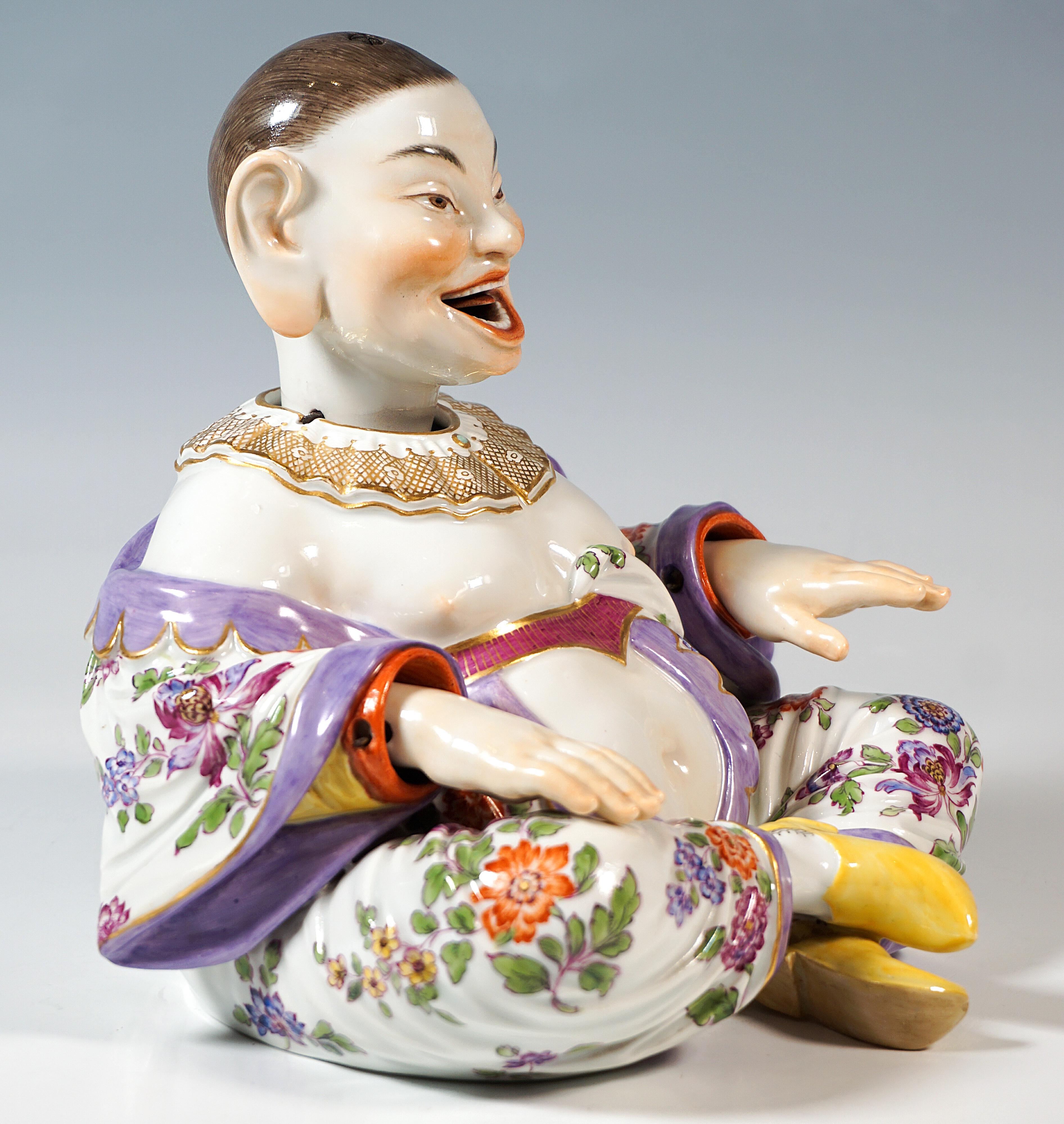 Representación de una figura de Buda sentado y sonriente de una serie de tipos populares. Cuerpo voluminoso con el pelo estrictamente peinado hacia atrás y una amplia túnica, sentada con las piernas cruzadas y los brazos rectos delante de ella.