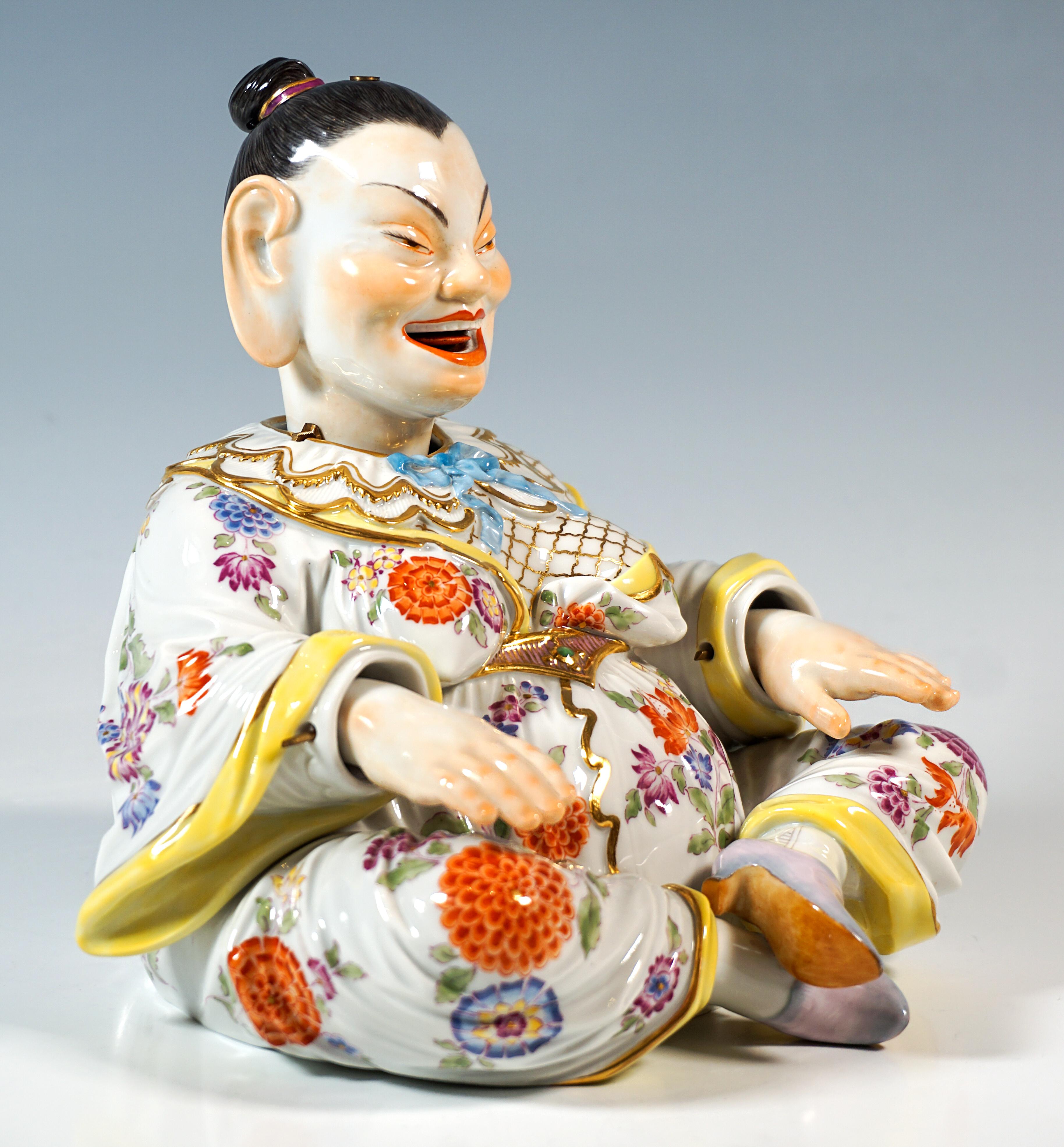 Représentation d'une figure de Bouddha assise et souriante, issue d'une série de types folkloriques. 
Corps féminin volumineux, cheveux strictement attachés et robe large, assis les jambes croisées, les bras tendus devant elle.
Tête, langue et mains