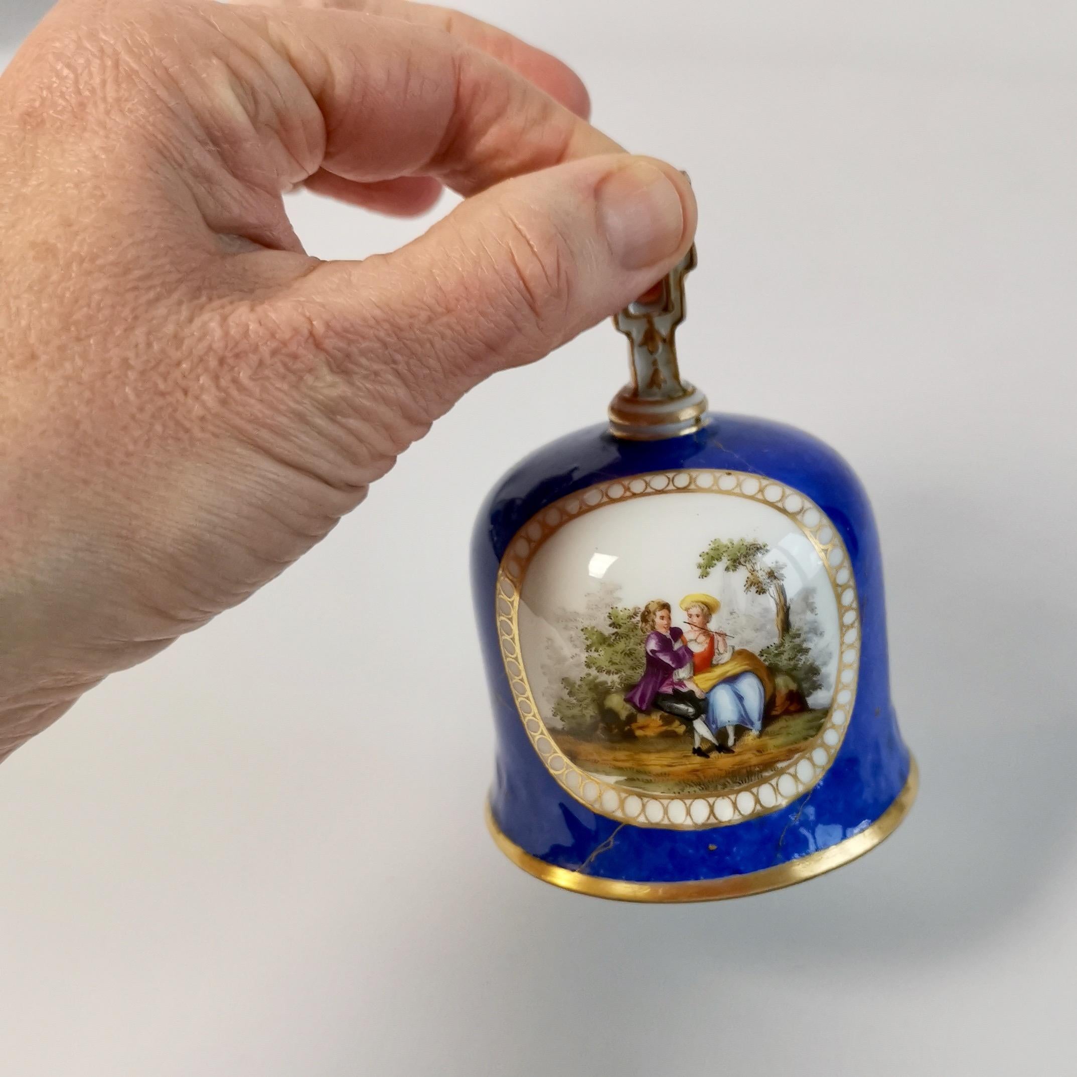 This is a very charming table bell made by Meissen in the 19th Century. The bell has a royal blue ground, slightly marbled with gilt, and two romantic scenes on either side. The bell has a light wooden clapper and a very clear sound.
 
The Meissen