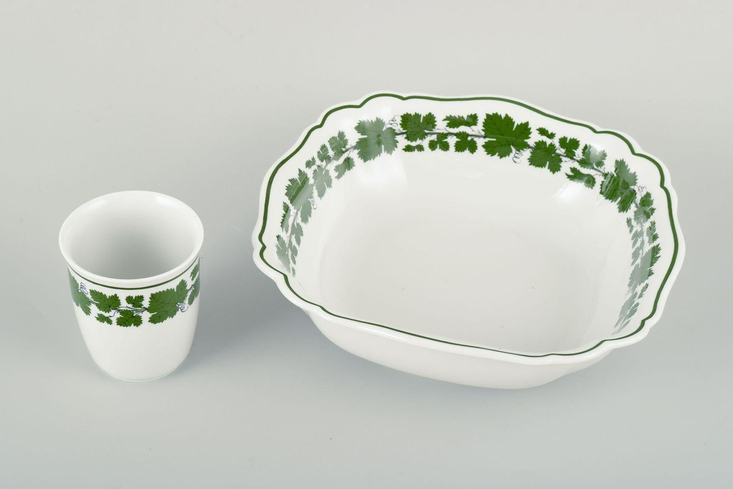 Meissen, Vase and Bowl, Vine-Leaf Pattern, “Voller grüner Weinkranz”.
Set consisting of a small vase and a bowl from Meissen, decorated in the classic Vine-Leaf Pattern (“Voller grüner Weinkranz”). 
Both pieces are adorned with green vine leaves and